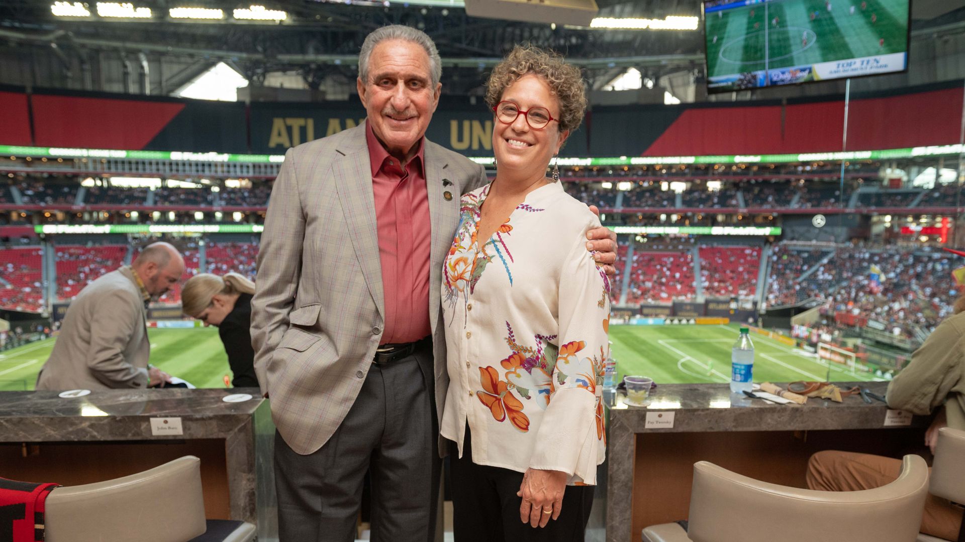 Arthur Blank and Fay Twersky stand together at a sports event smiling
