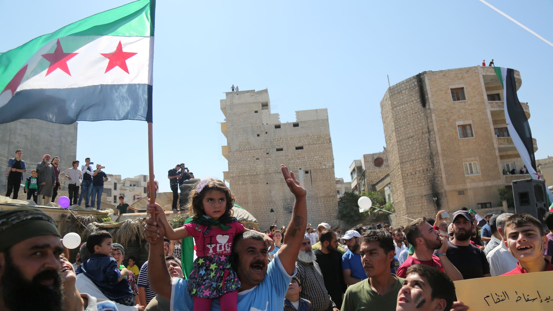 People of Idlib hold a Syrian revolution flag during a demonstration to demand the international community stop the military campaign by Syrian regime