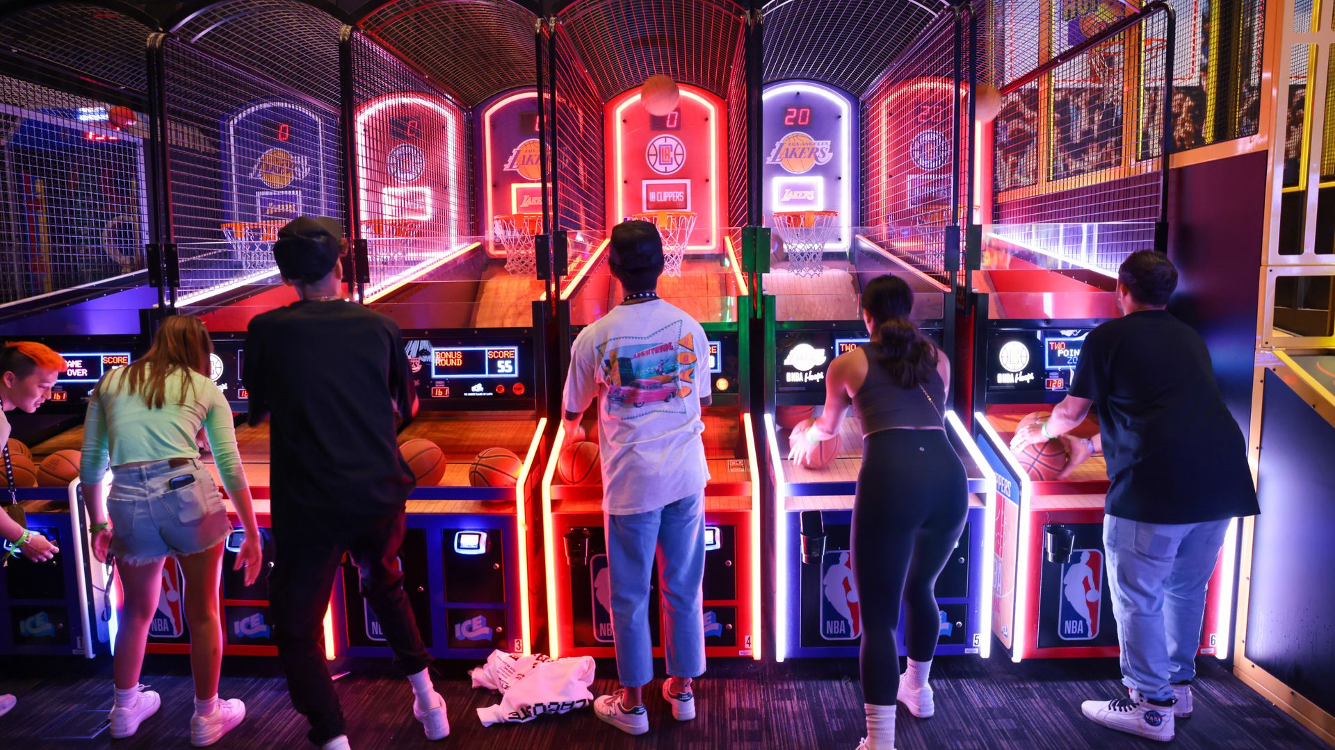 Arcade goers compete in a basketball shooting game