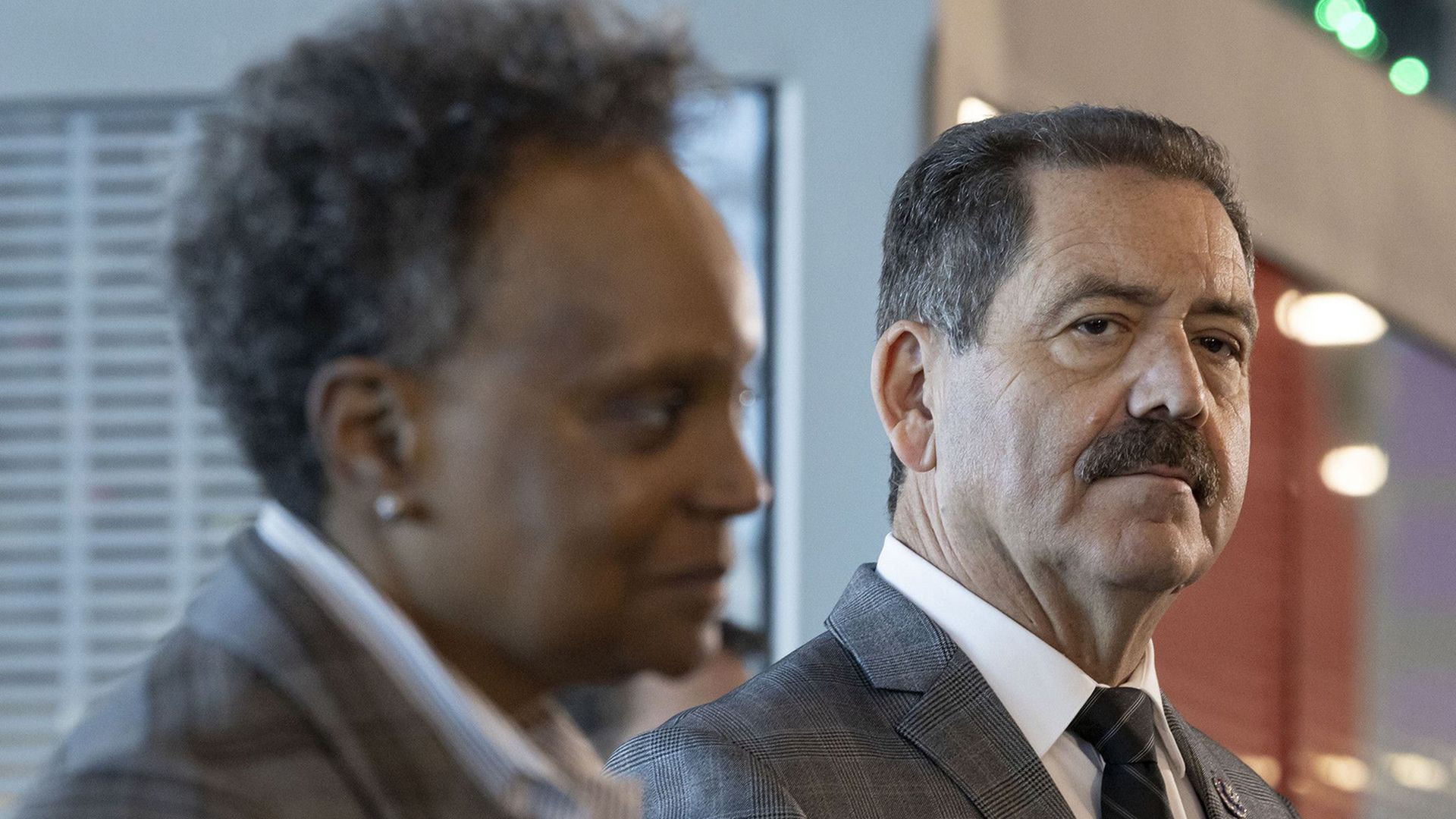 Photo of two people talking to press at a press conference. 