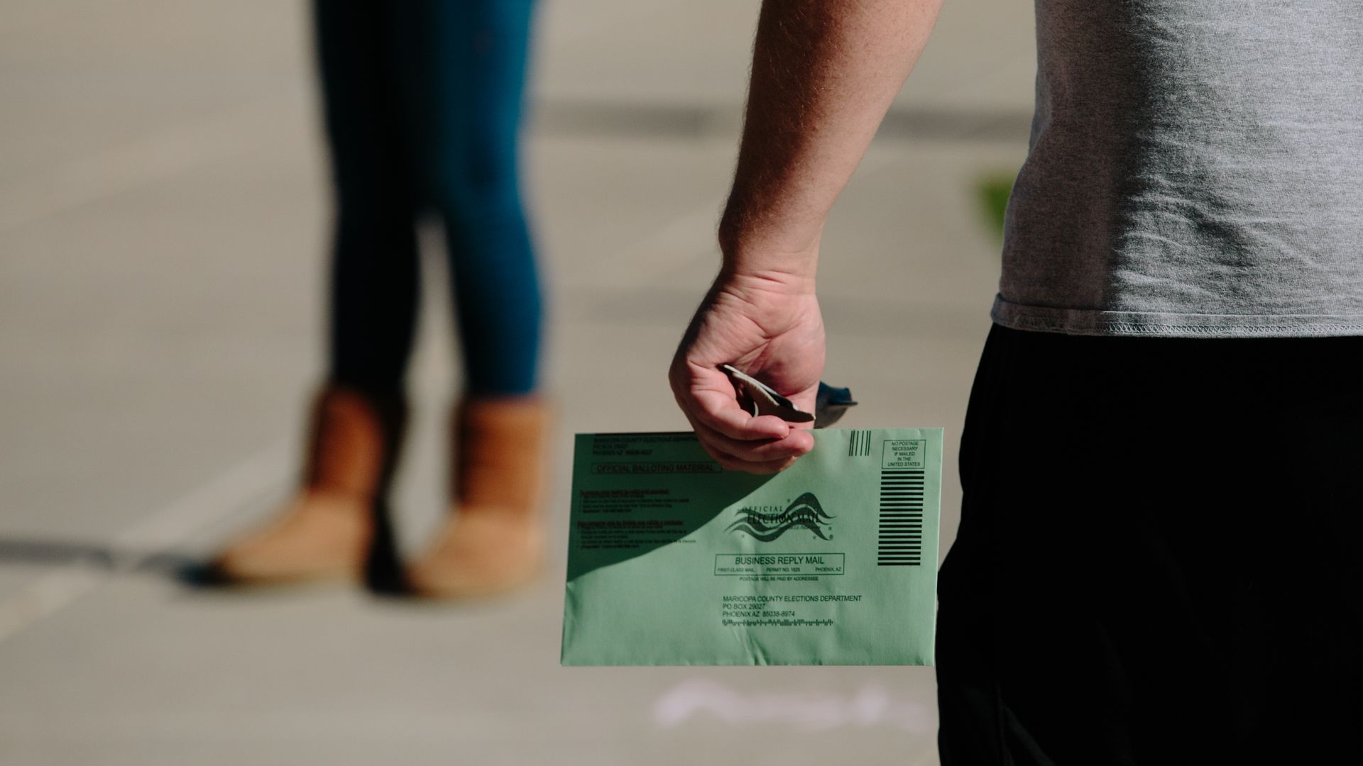 A man holds a green envelope containing an early ballot in Maricopa County in Arizona. 