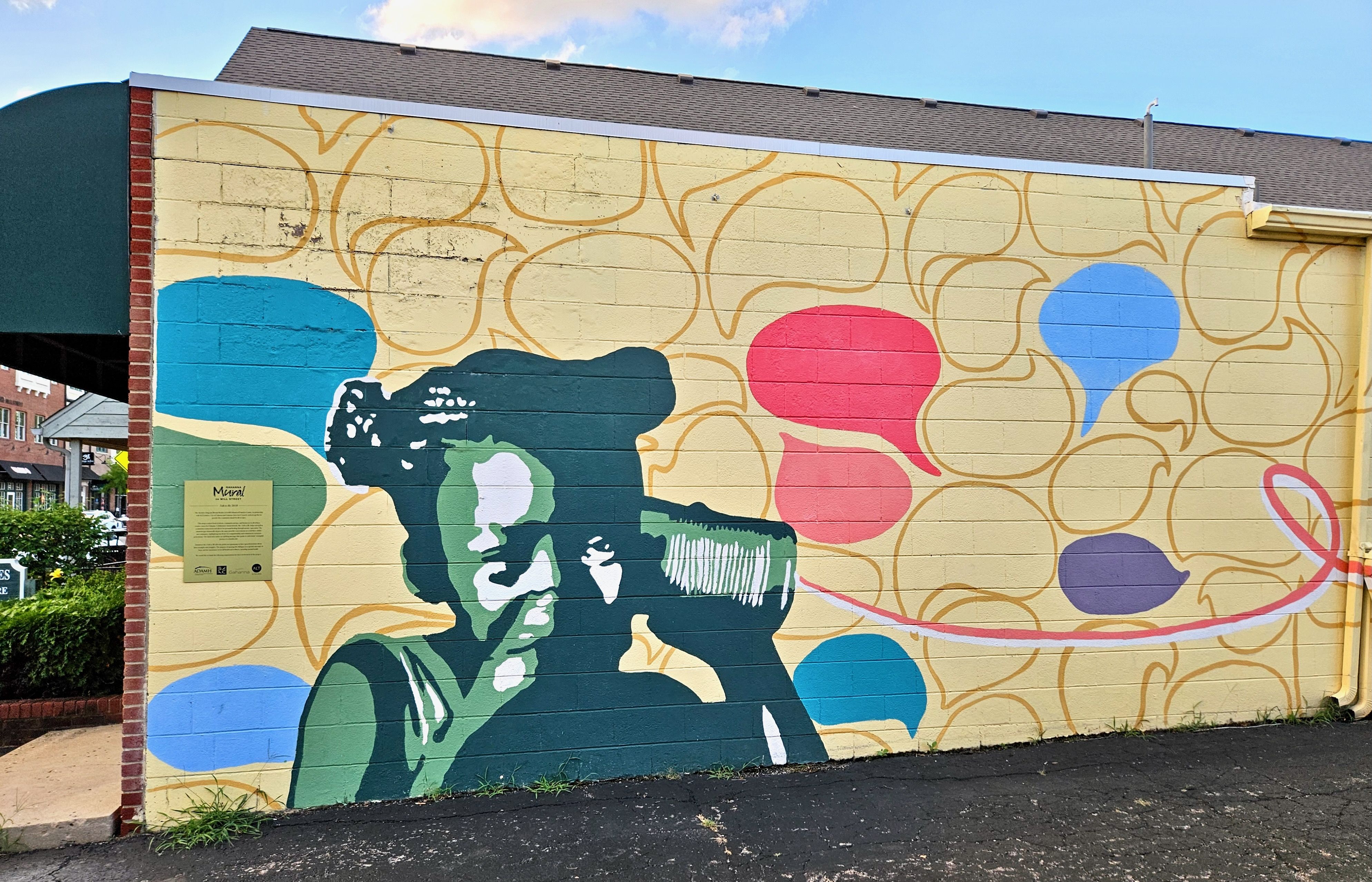 A colorful mural depicting a girl listening into a tin can