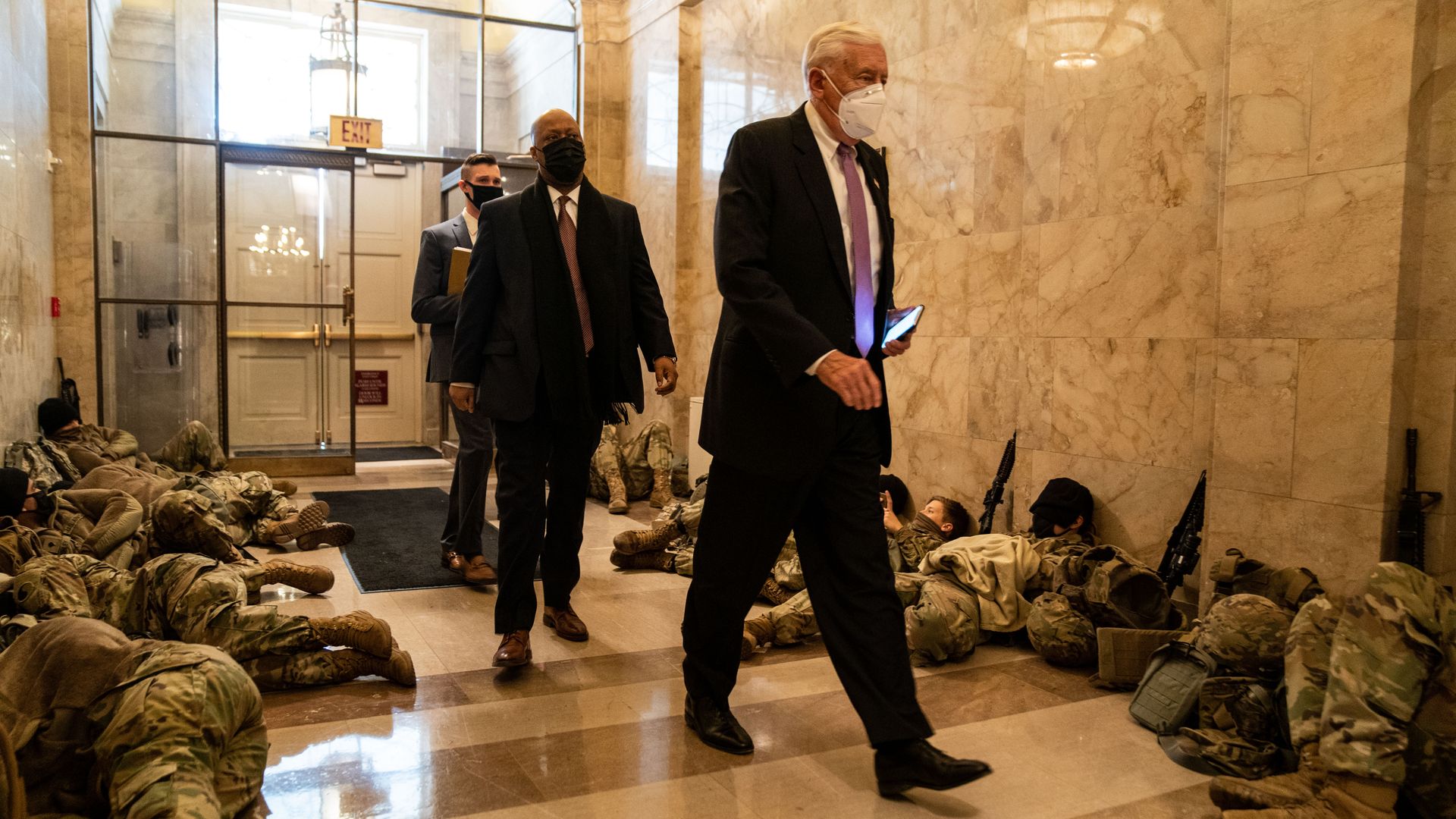Picture of Steny Hoyer walking past National Guard members sleeping in the halls of Capitol Hill