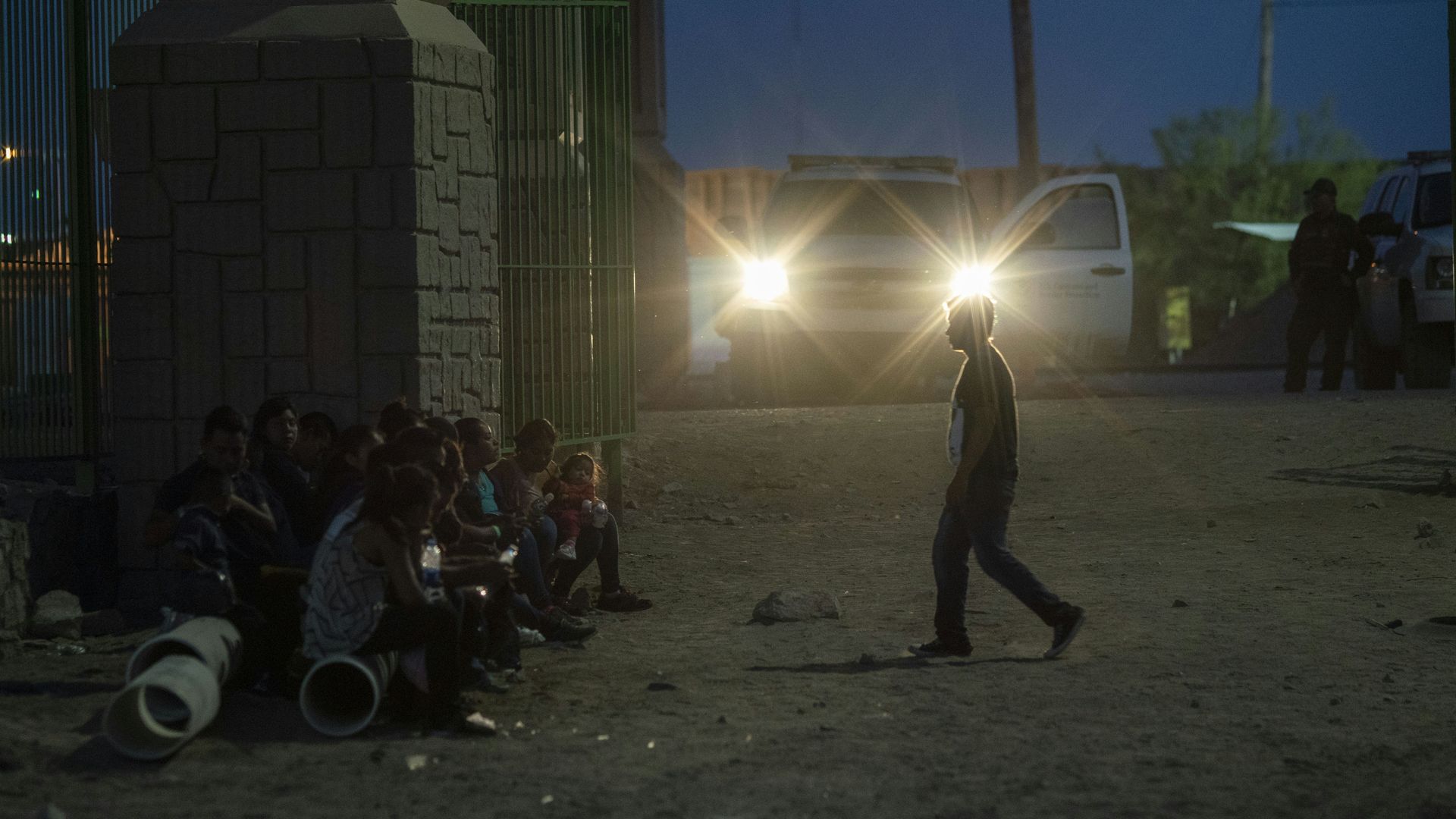 Migrants waiting in the dark near the border to be taken to a border patrol processing center.