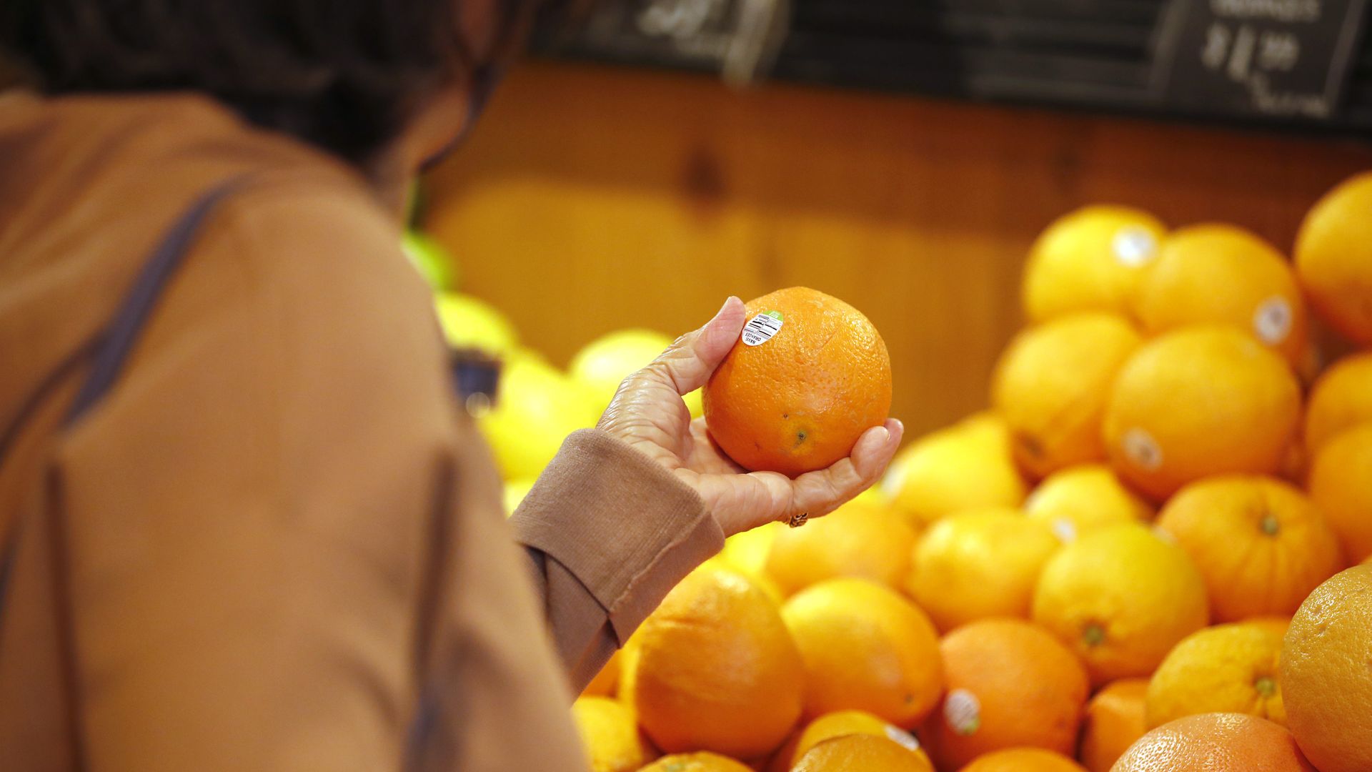 A woman shops for oranges in a supermarket.