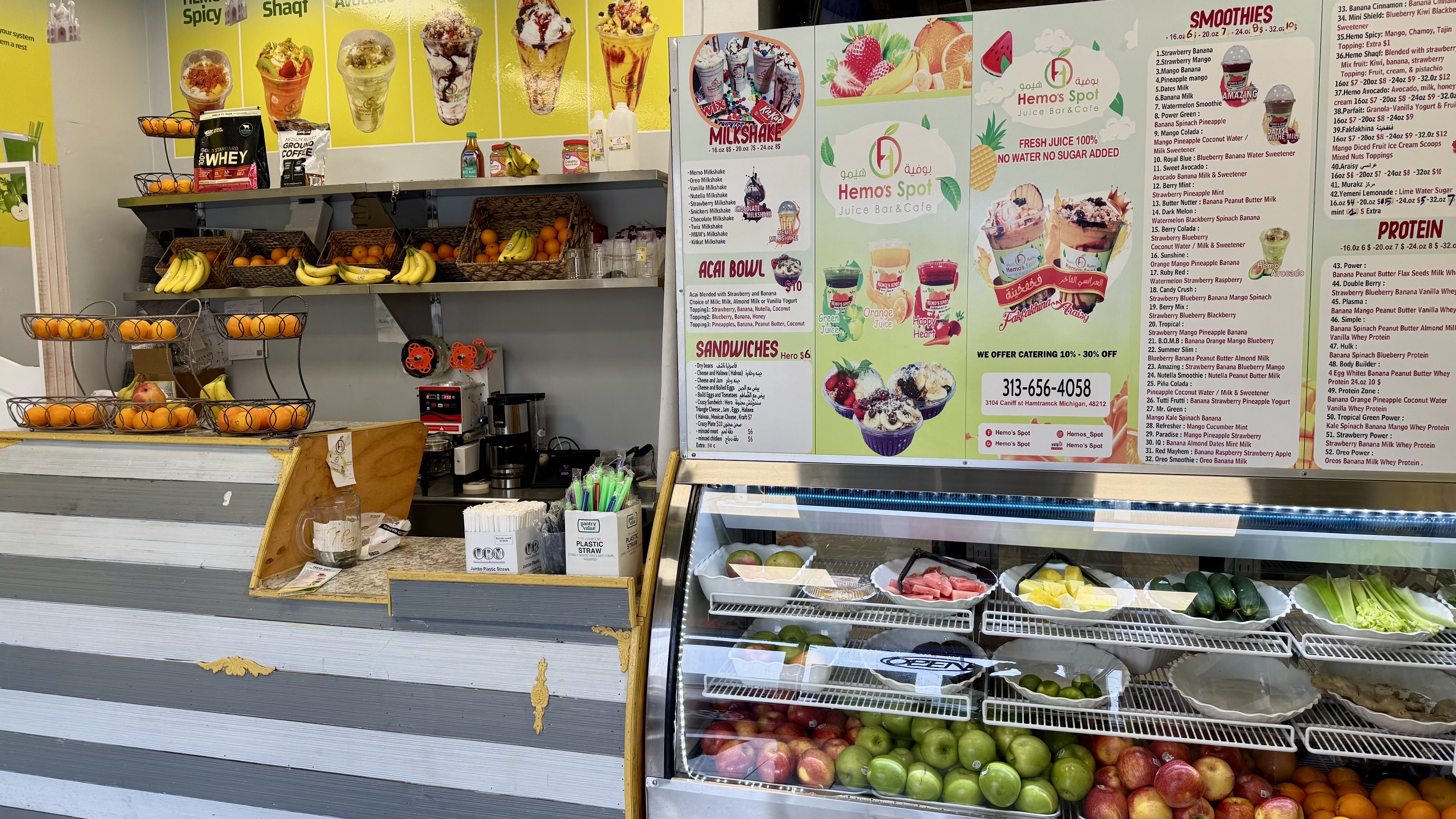 A counter with a ton of fresh fruit and a giant menu