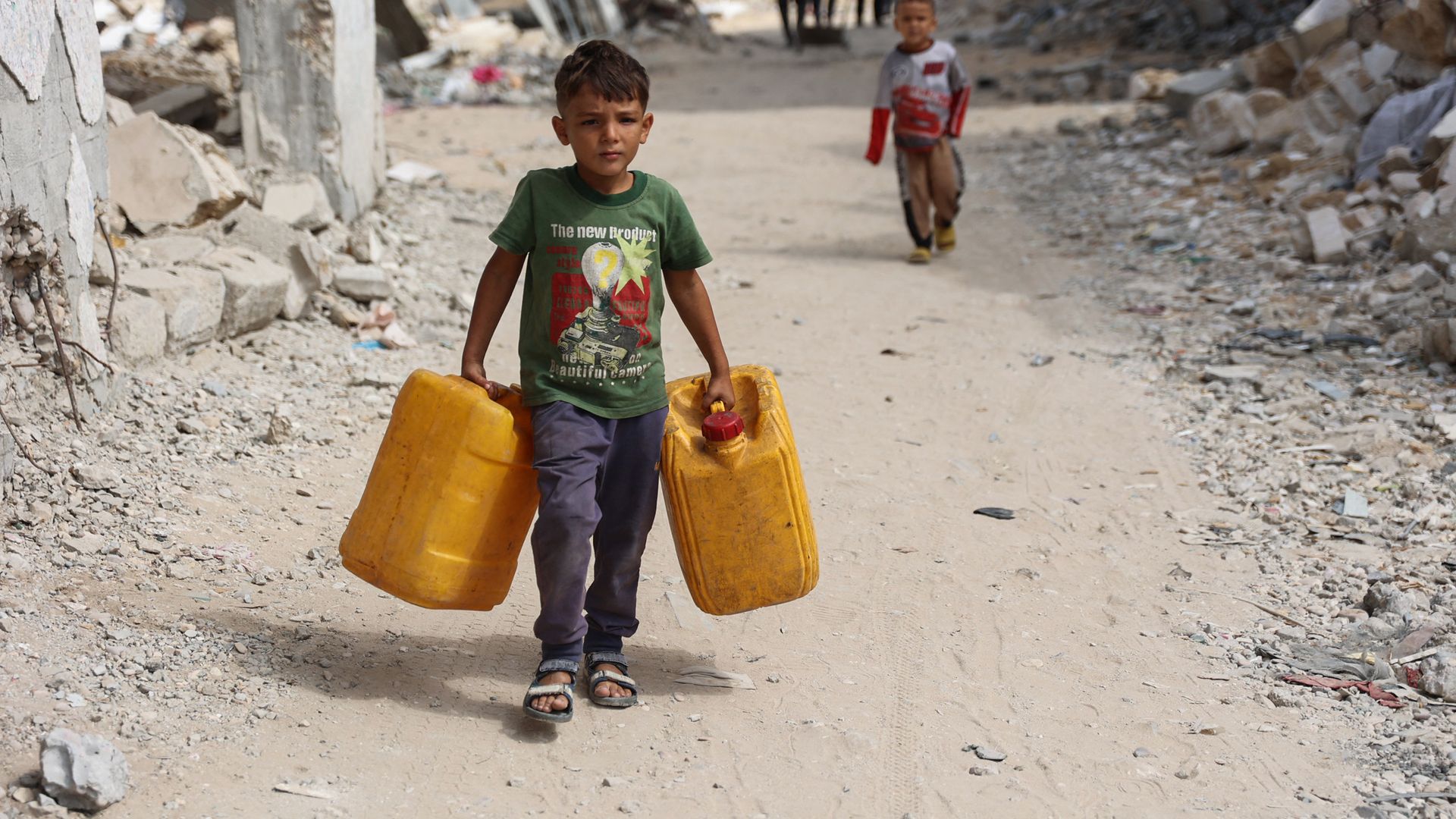 Displaced Palestinian youths carry containers to ferry water from a distribution point in the Shujaiya neighbourhood of Gaza City on October 7, 2024,