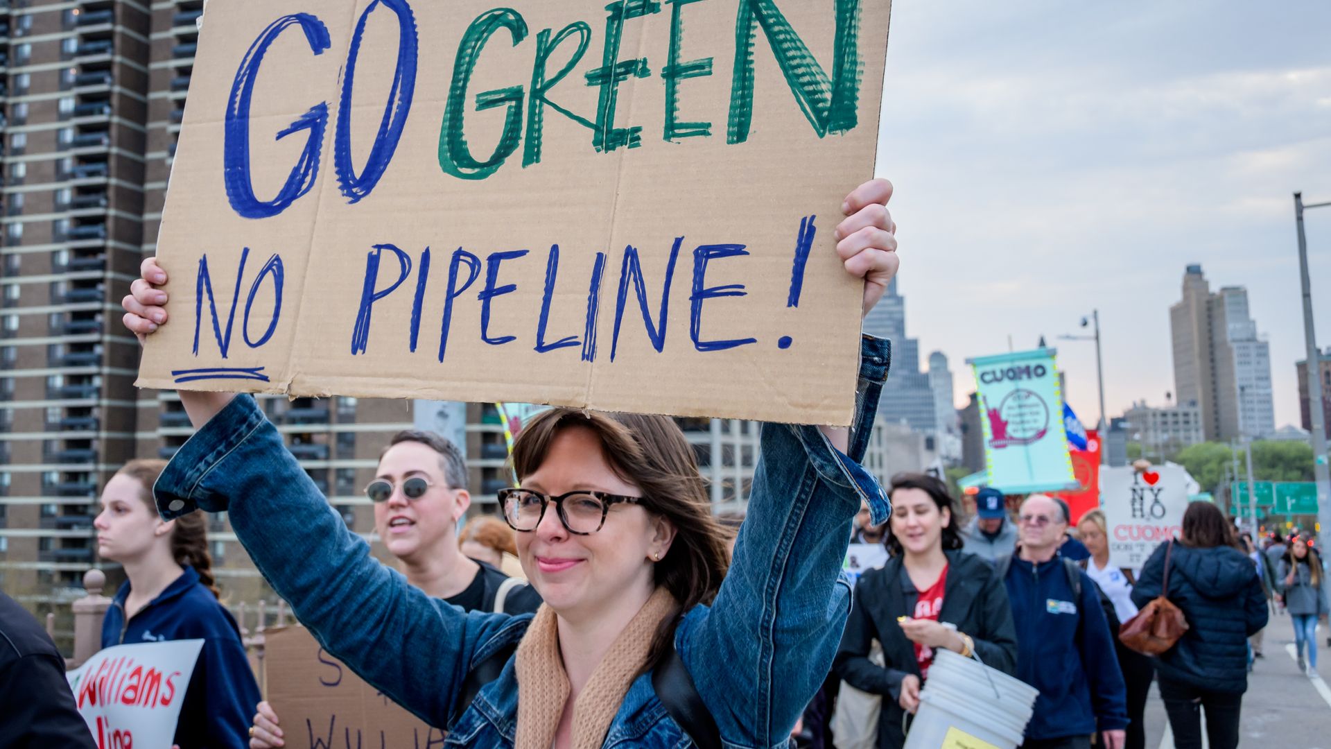 Photo of a climate activist holding a sign with the words "Go green, no pipeline!"