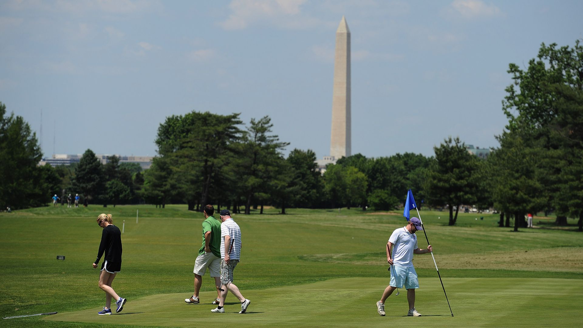 Golfers walk on the East Potomac course with the Washington Monument in the background