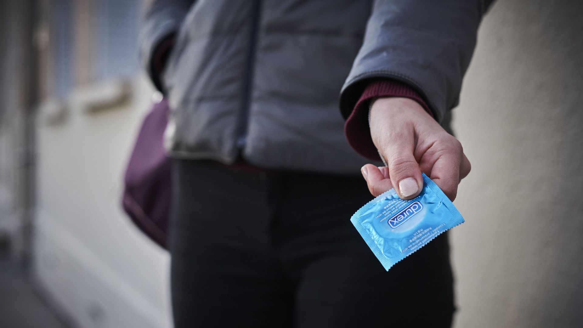 A person holds a condom. 