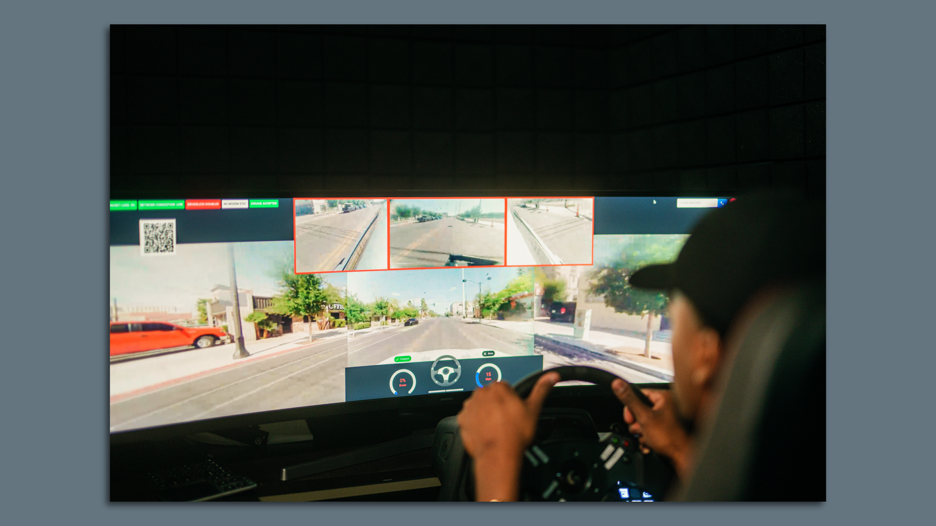 Image of a remote operator at a computer screen driving a car on a real road