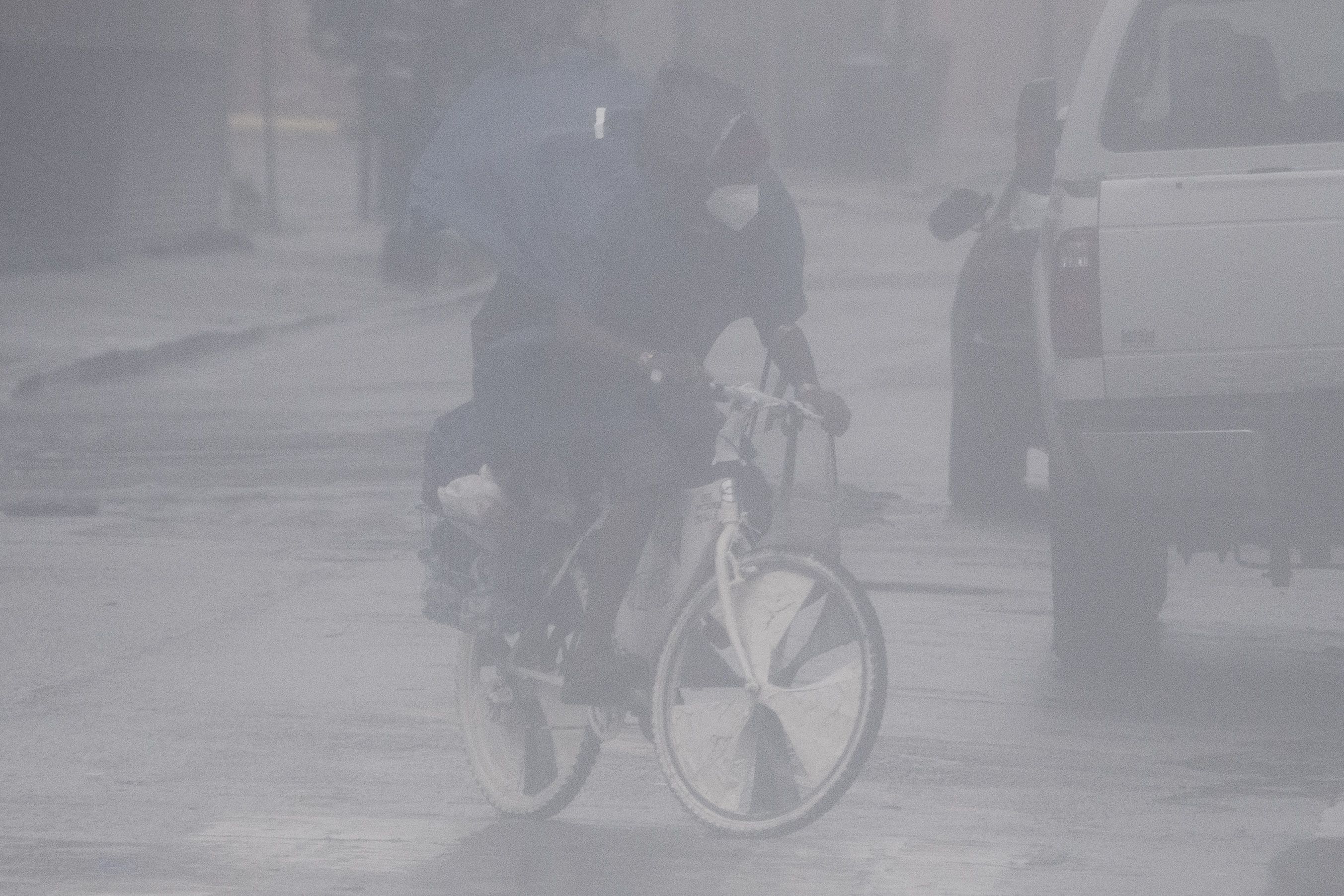 A cyclist wears a face mask as they ride through rain and high winds on Canal Street in New Orleans, Louisiana on August 29