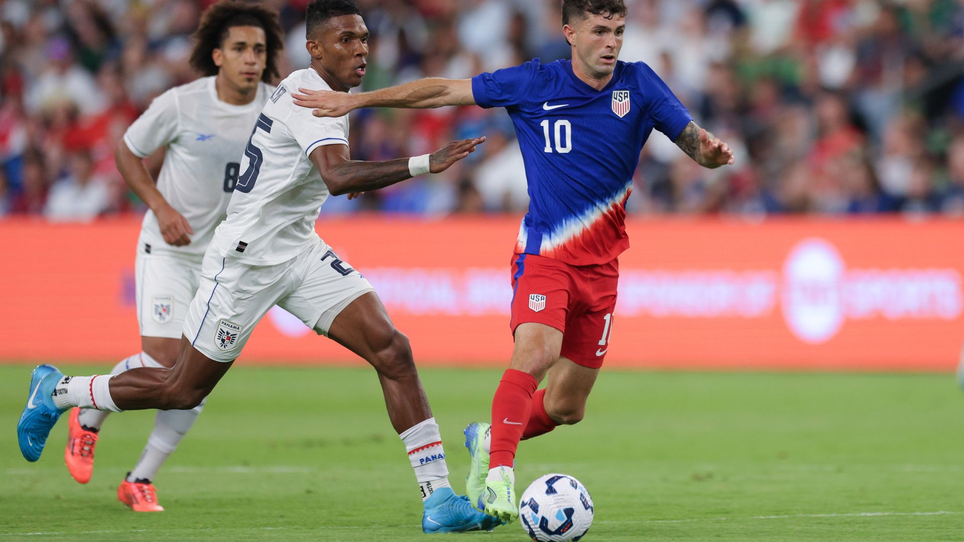 A U.S. men's player dribbles ahead of a Panamanian defender.