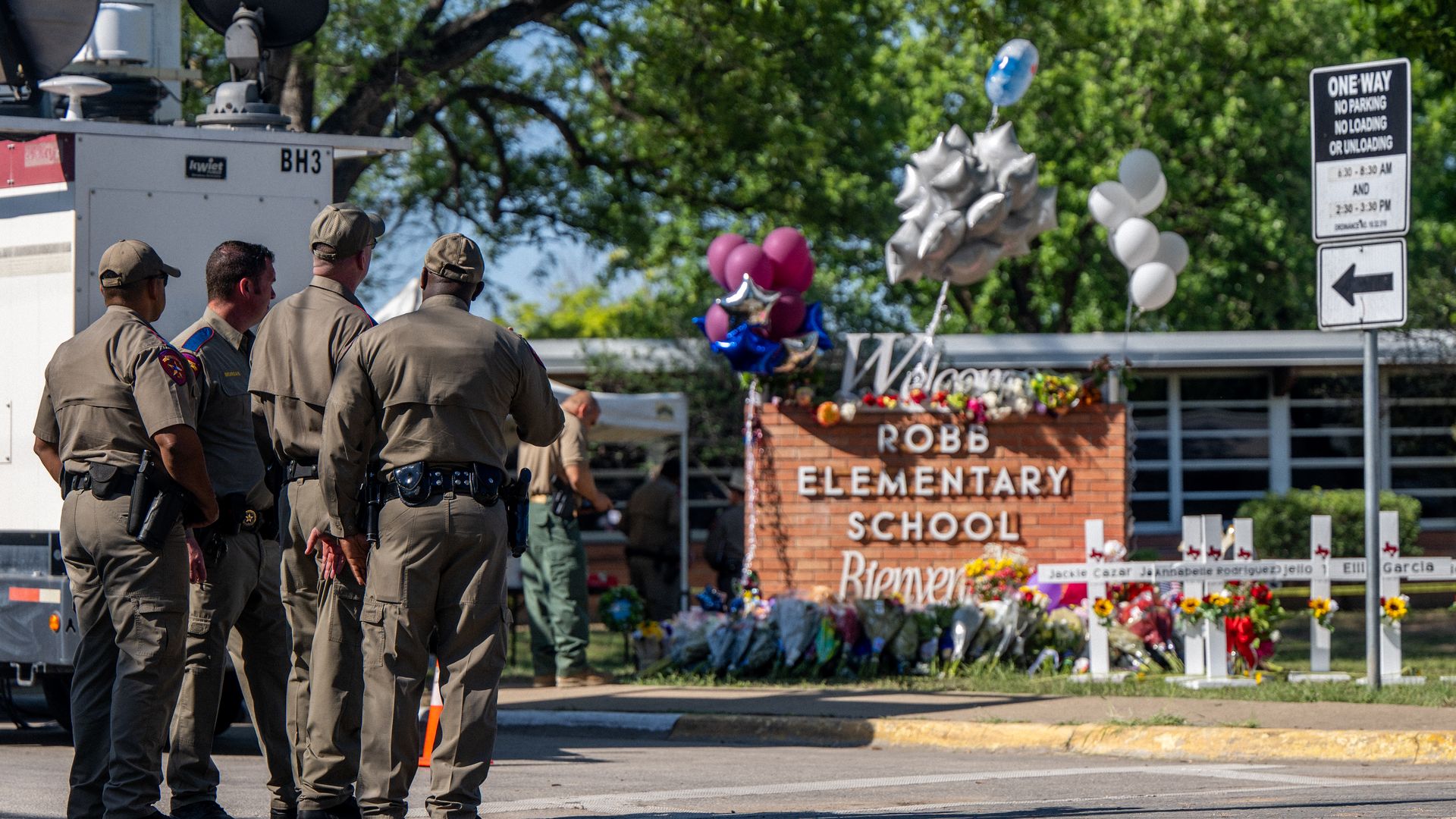 Law enforcement officers stand looking at a memorial following a mass shooting at Robb Elementary School on May 26, 2022 in Uvalde, Texas.