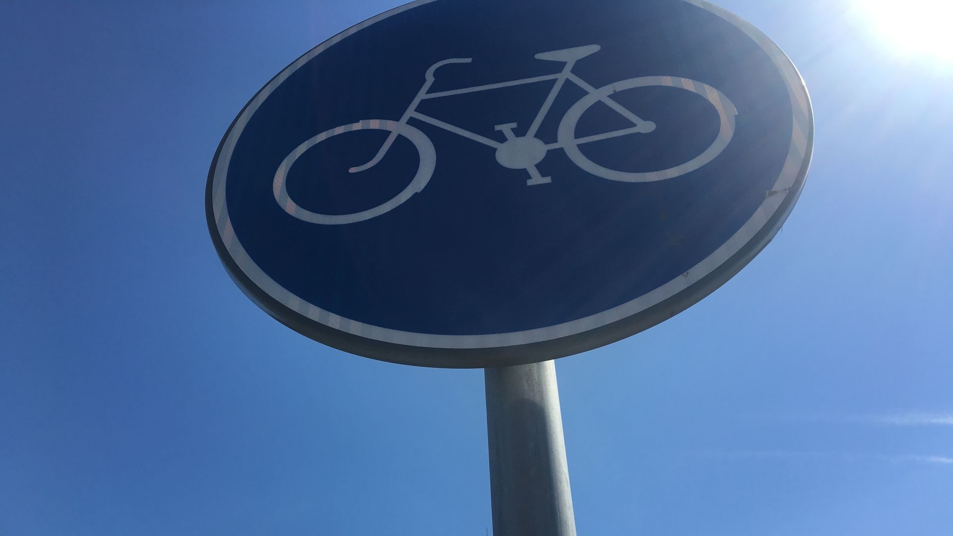 A photo of a blue street sign with a white bicycle outline to indicate a bike lane.