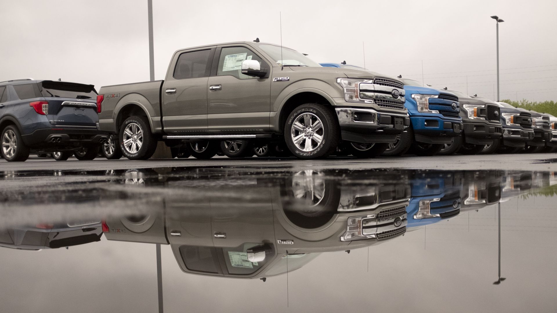 Pickup trucks sitting in a row on a rainy dealership lot