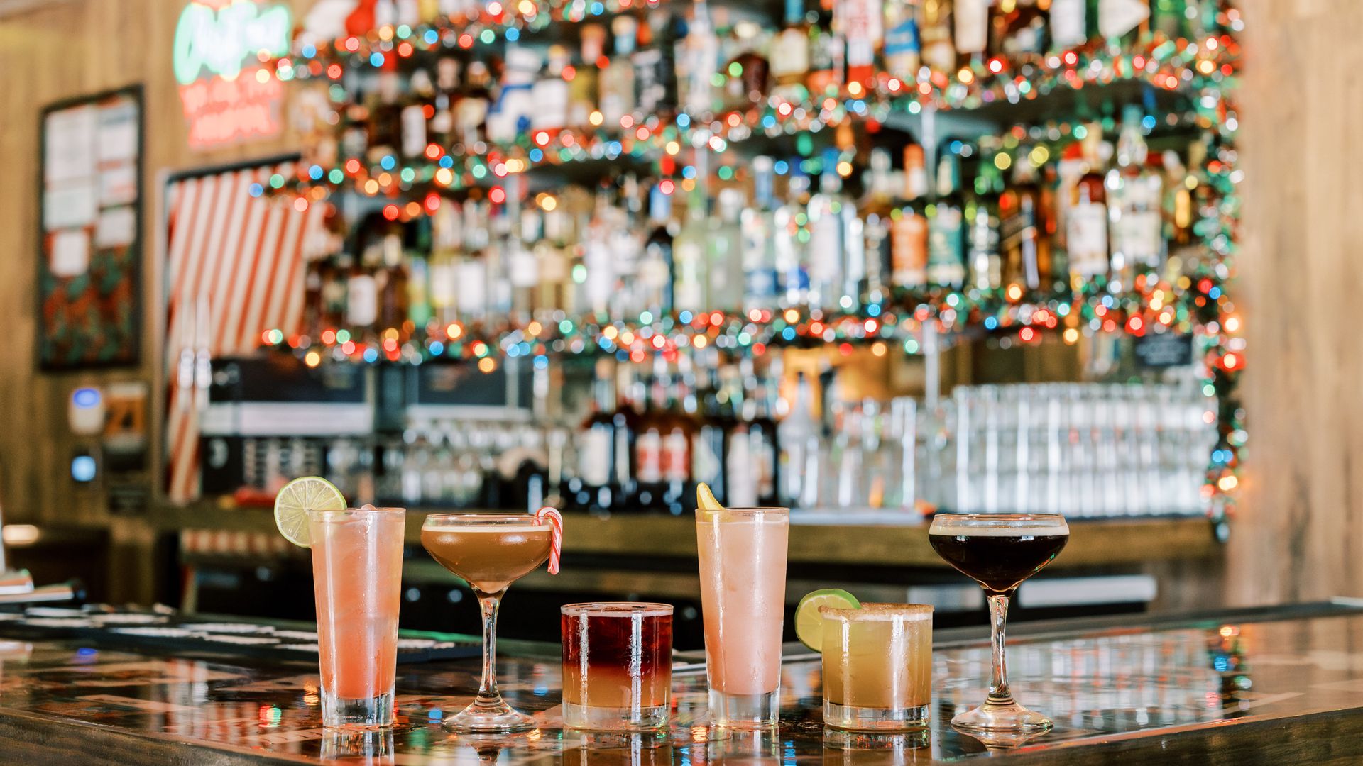 A photo of festive drinks on a bar with Christmas lights in the background.