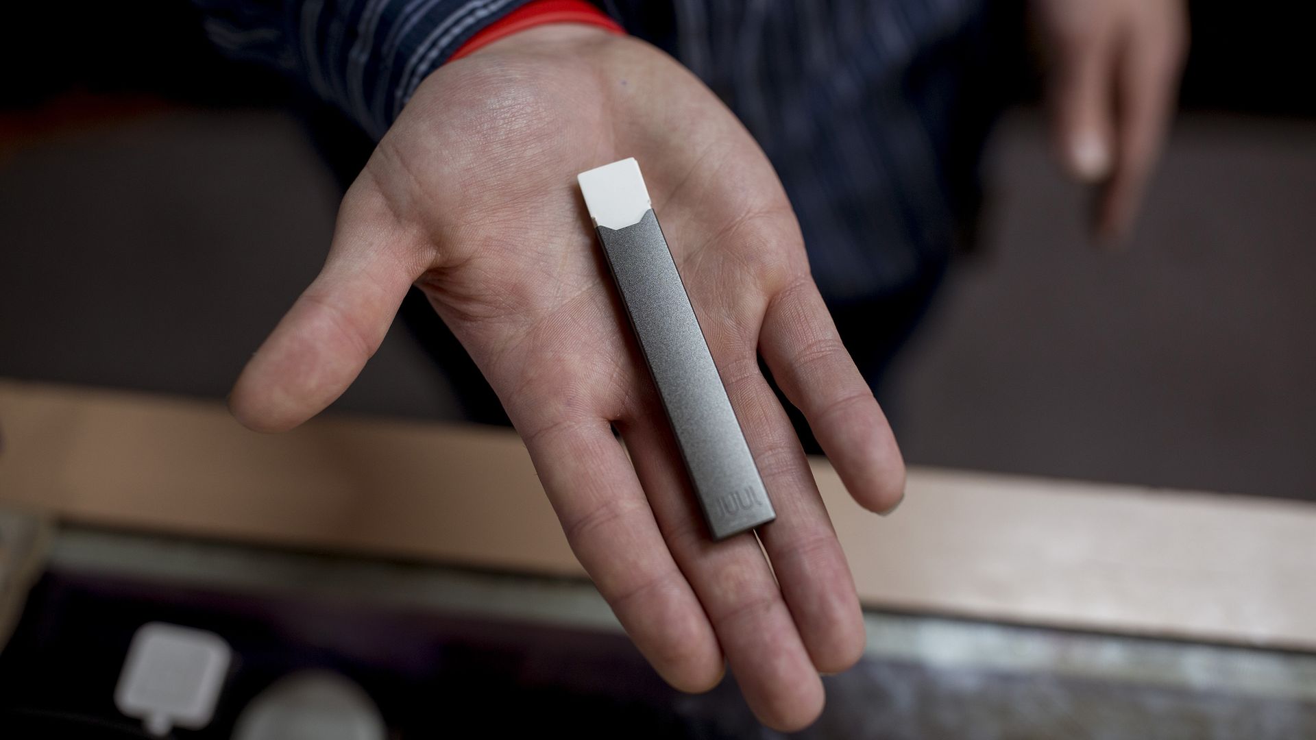 Palm of someone's hand holding a Juul e-cigarette
