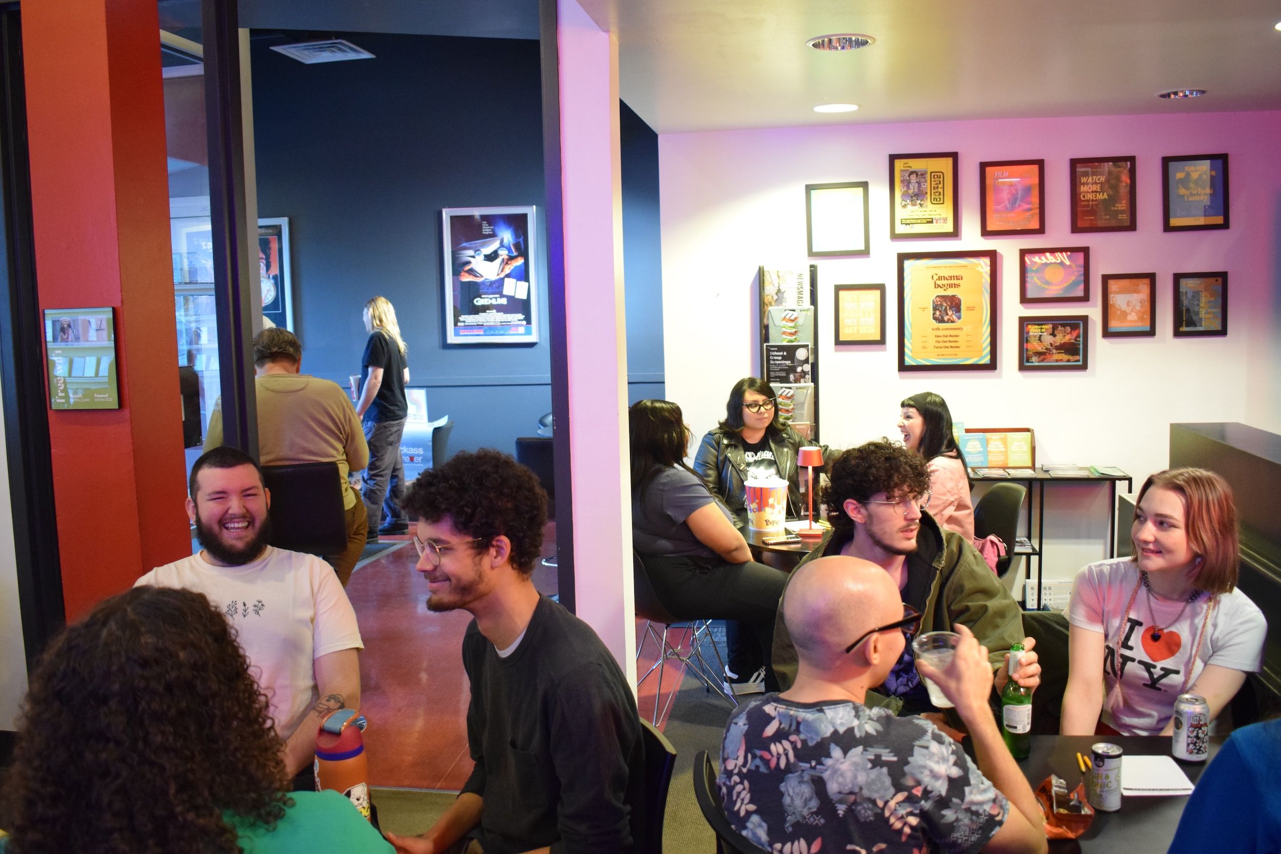 People sitting at tables in front of a wall with photos on the wall.