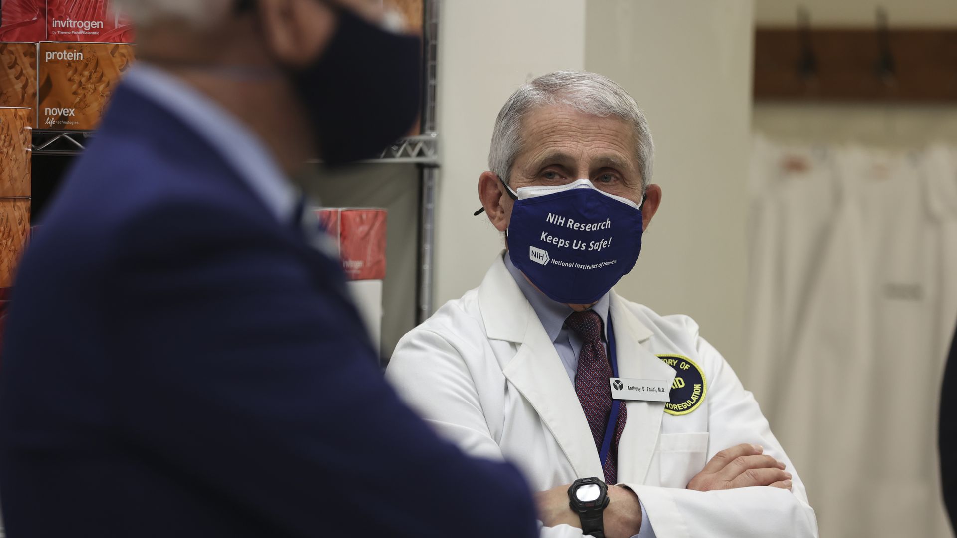 Anthony Fauci, director of the National Institute of Allergy and Infectious Diseases, wears a protective mask while listening to U.S. President Joe Biden, left