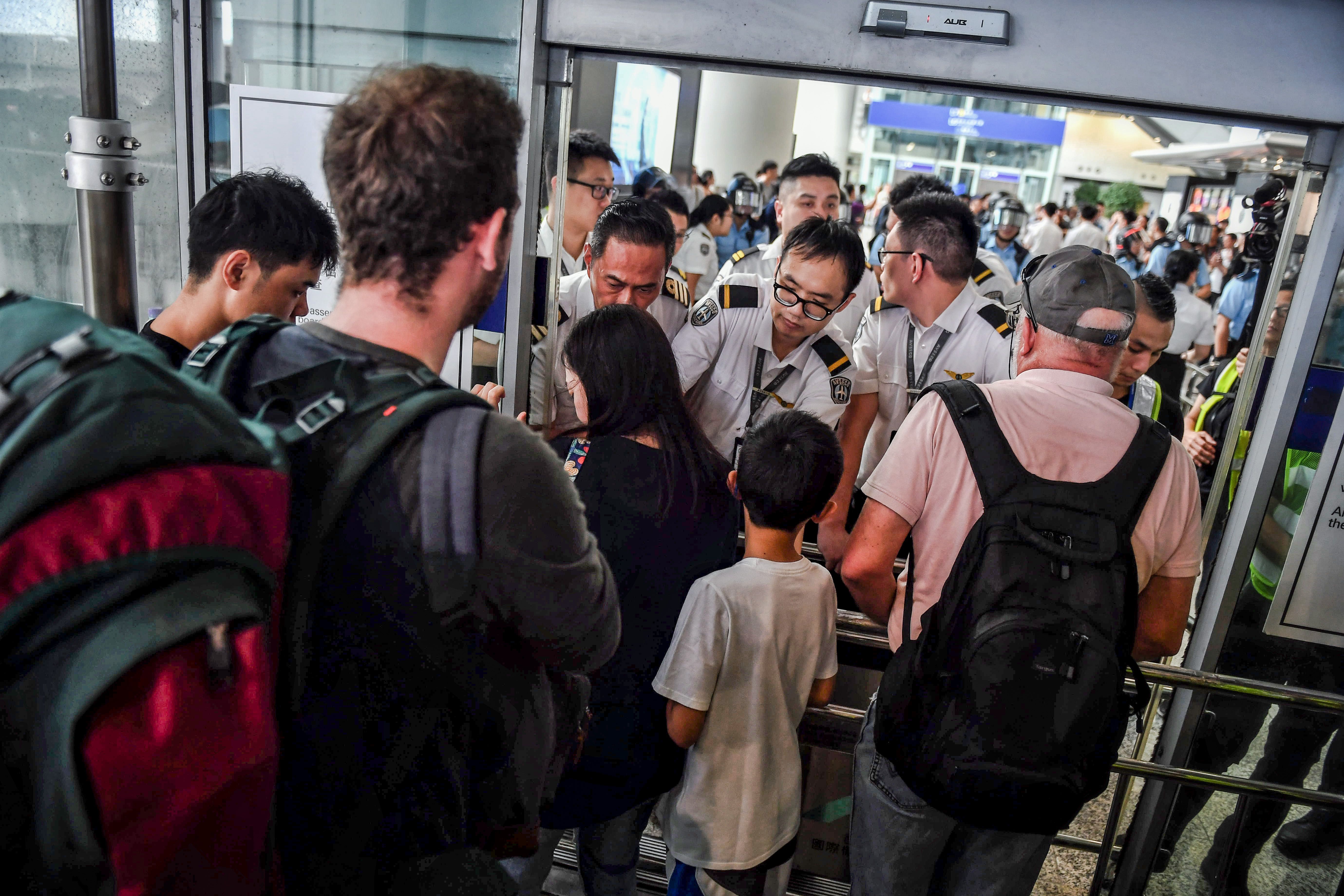Officials assist arriving passengers near a blockade set up by protesters at Hong Kong International Airport on Sunday.