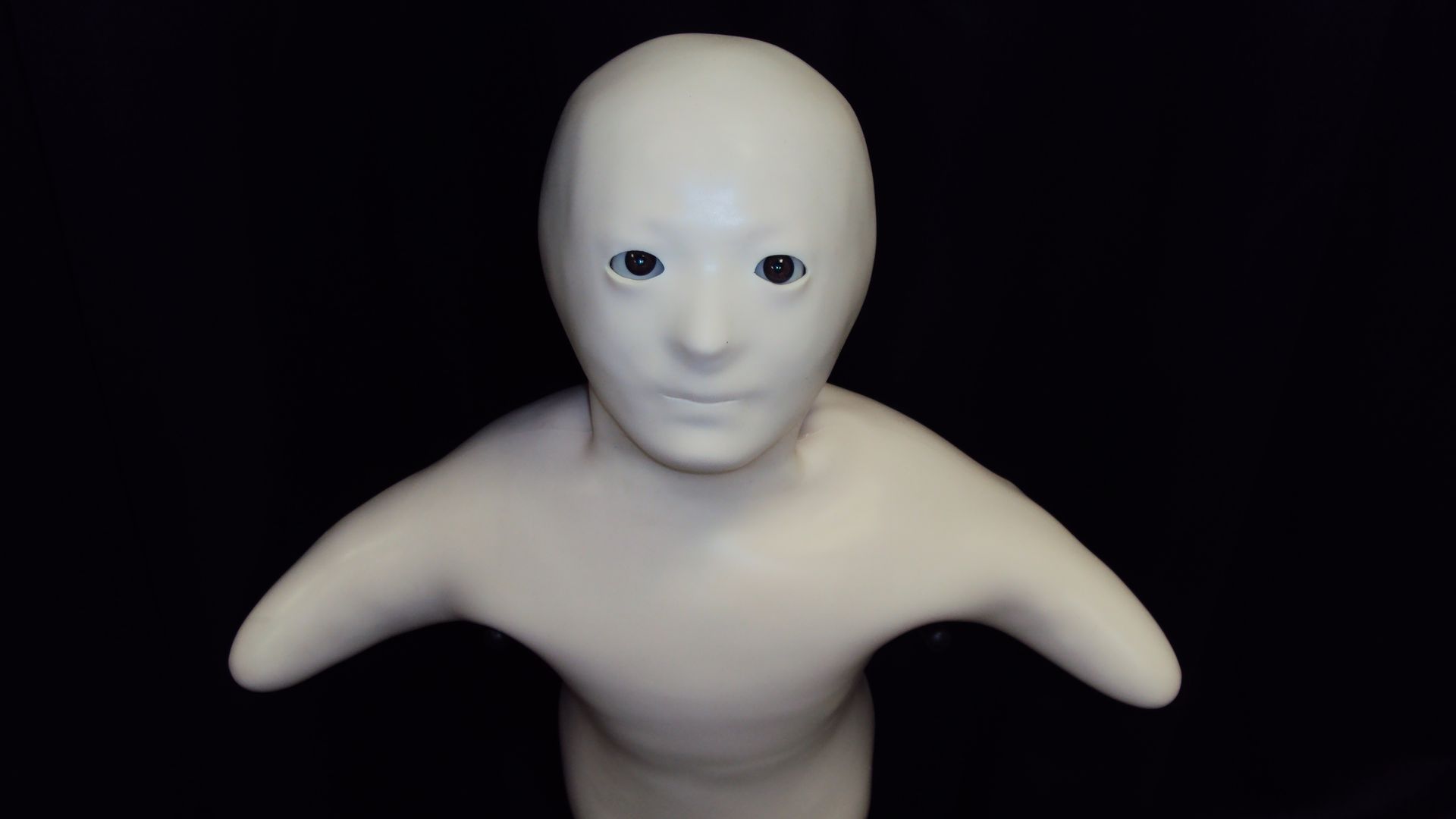 A white, baby-like robot on a dark background