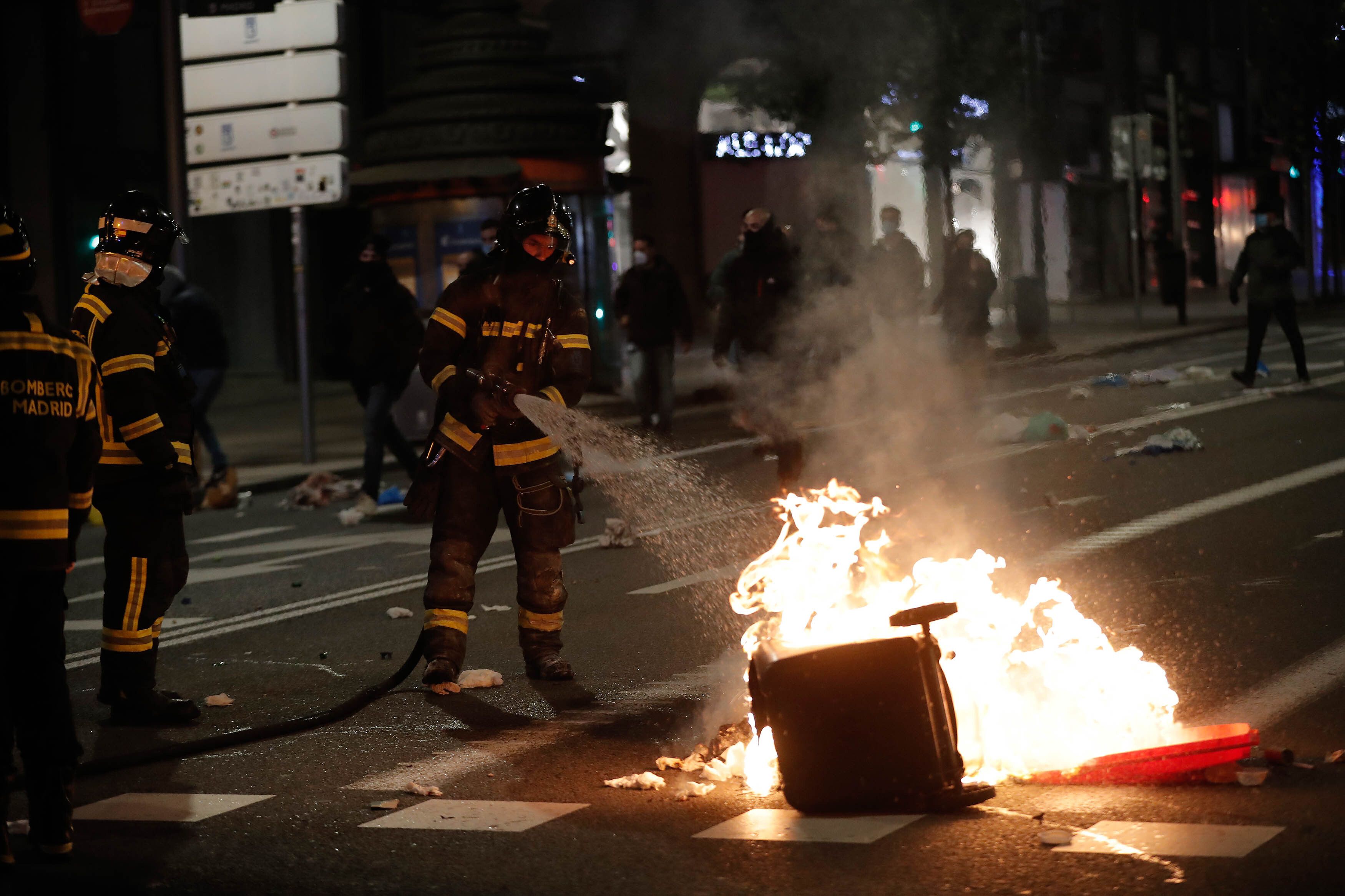 Firefighter team extinguish fire during a protest against the government's coronavirus (Covid-19) pandemic restrictions on Granvia Avenue in Madrid, Spain on November 01