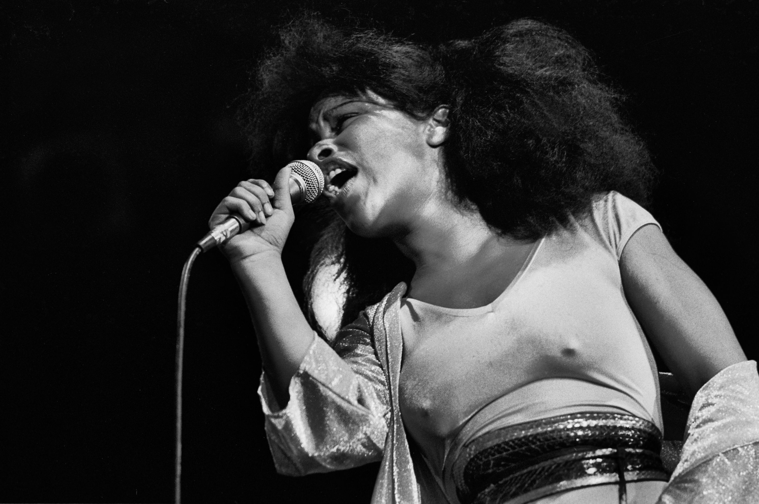 Photo of a woman singing in to a microphone 