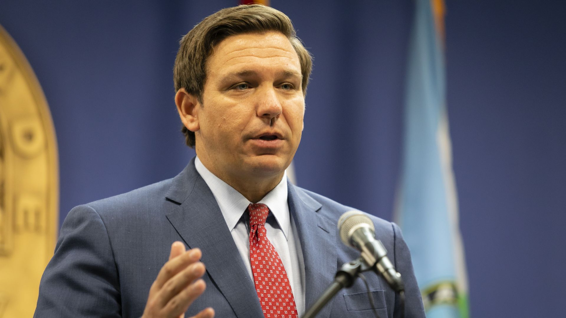 Ron DeSantis stands in a suit and tie 