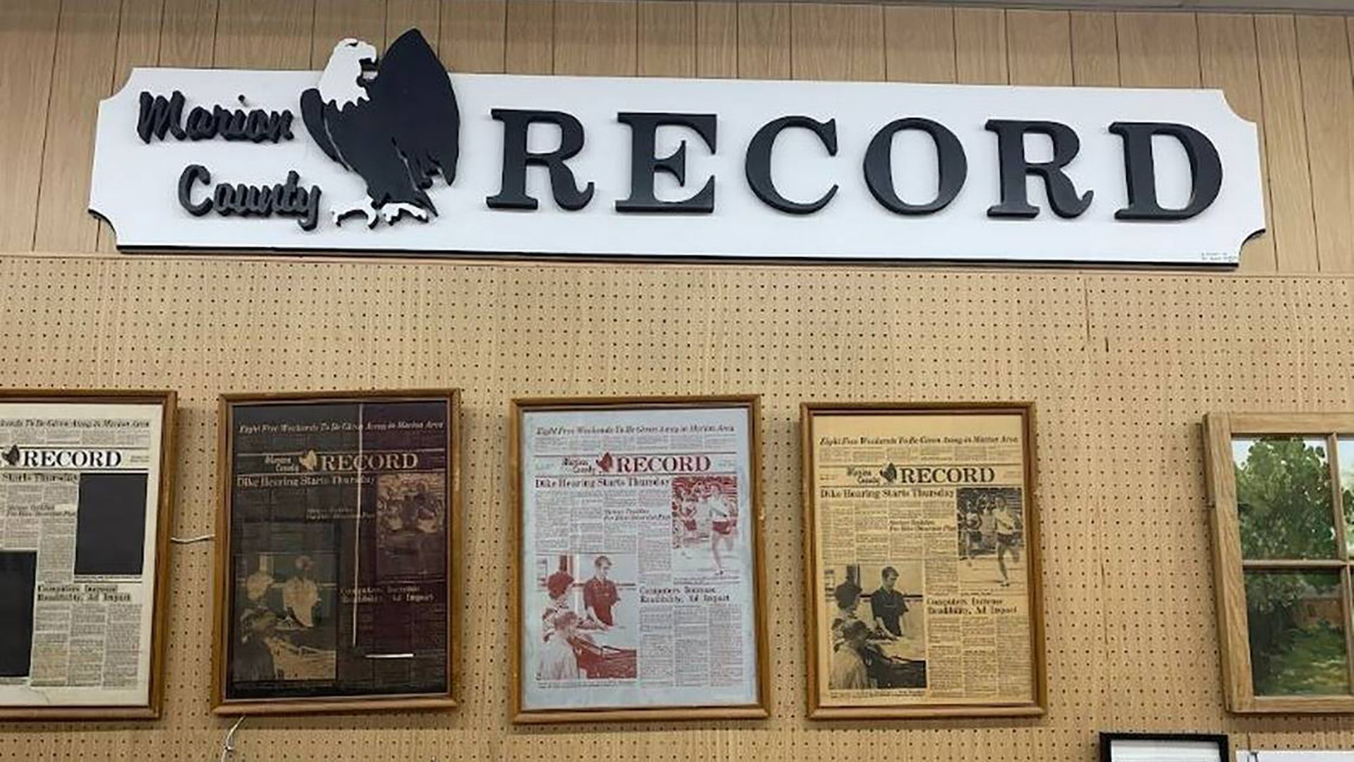 A wall of the newsroom with front pages framed