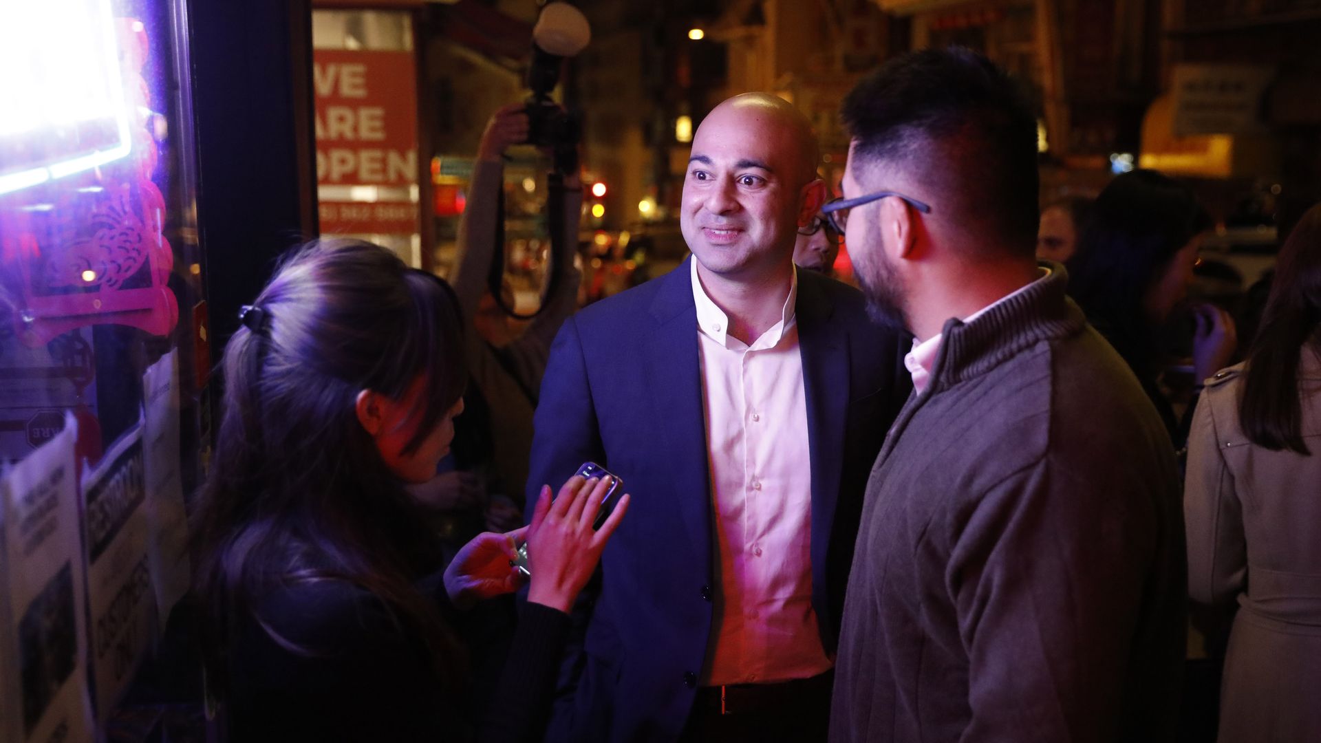 Photo of Bilal Mahmood smiling while standing between two people