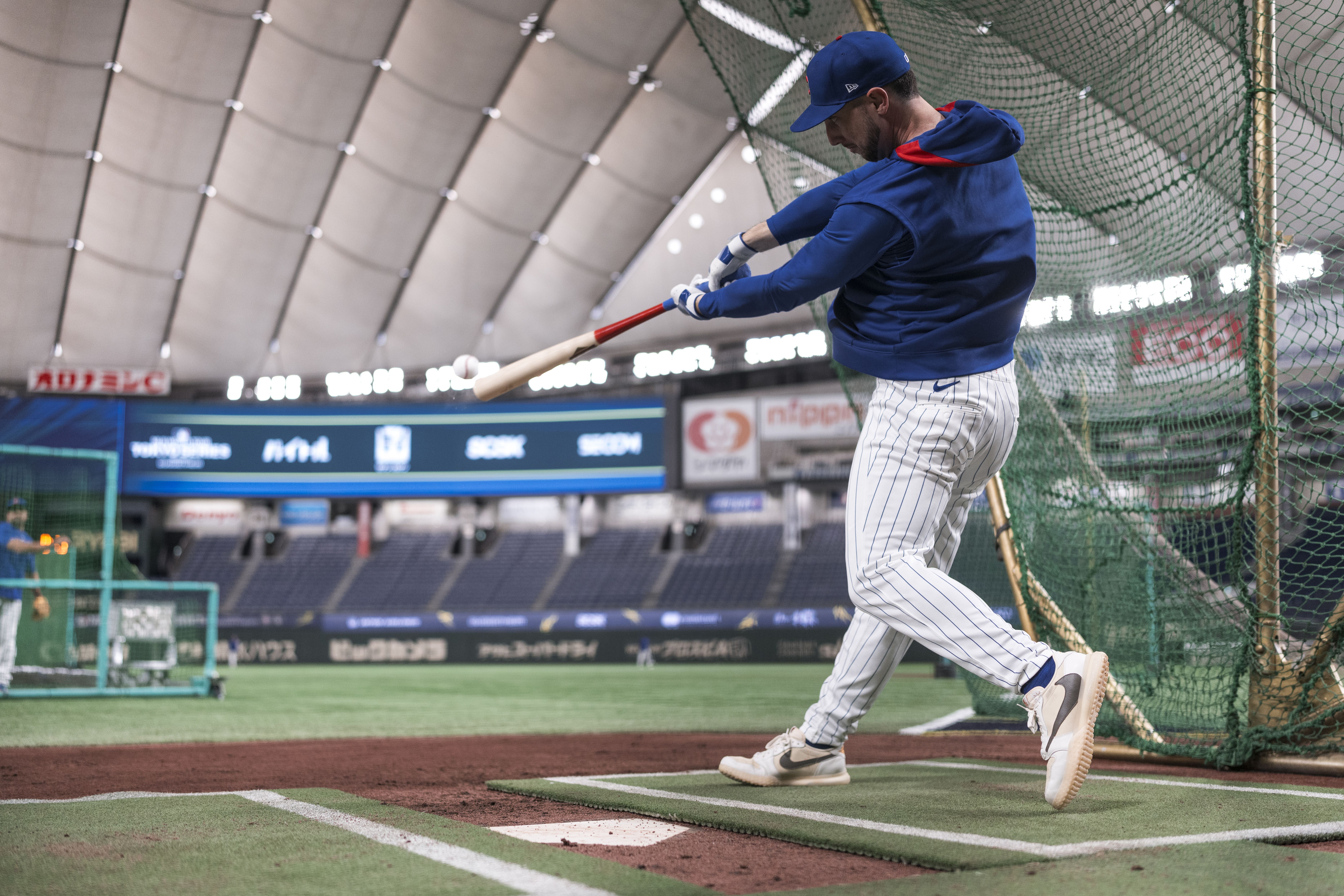 Photo of a baseball player swinging a bat and hitting a ball inside a domed stadium. 