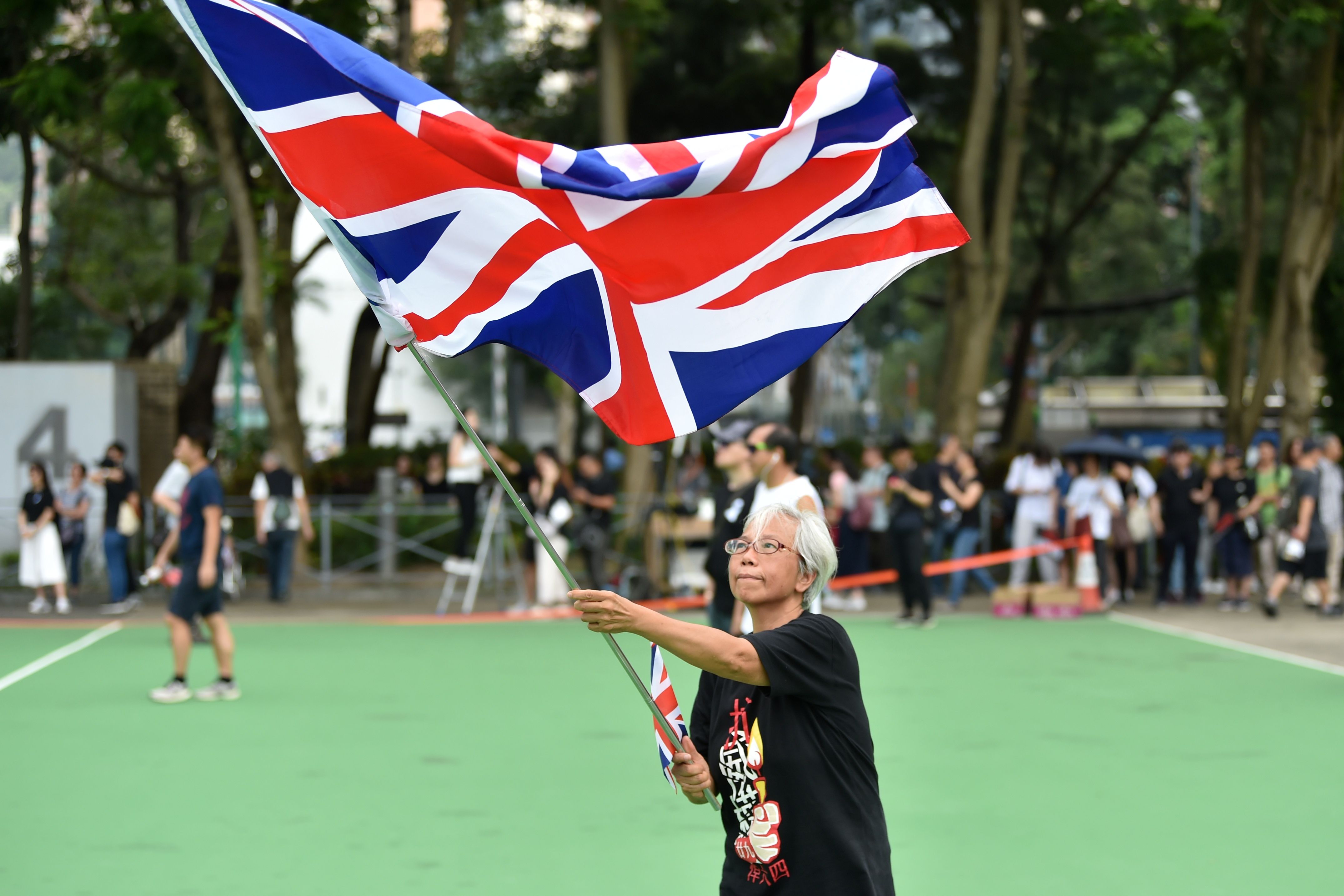 A woman waves a British flag as protesters gather to take part in a new rally in Hong Kong.