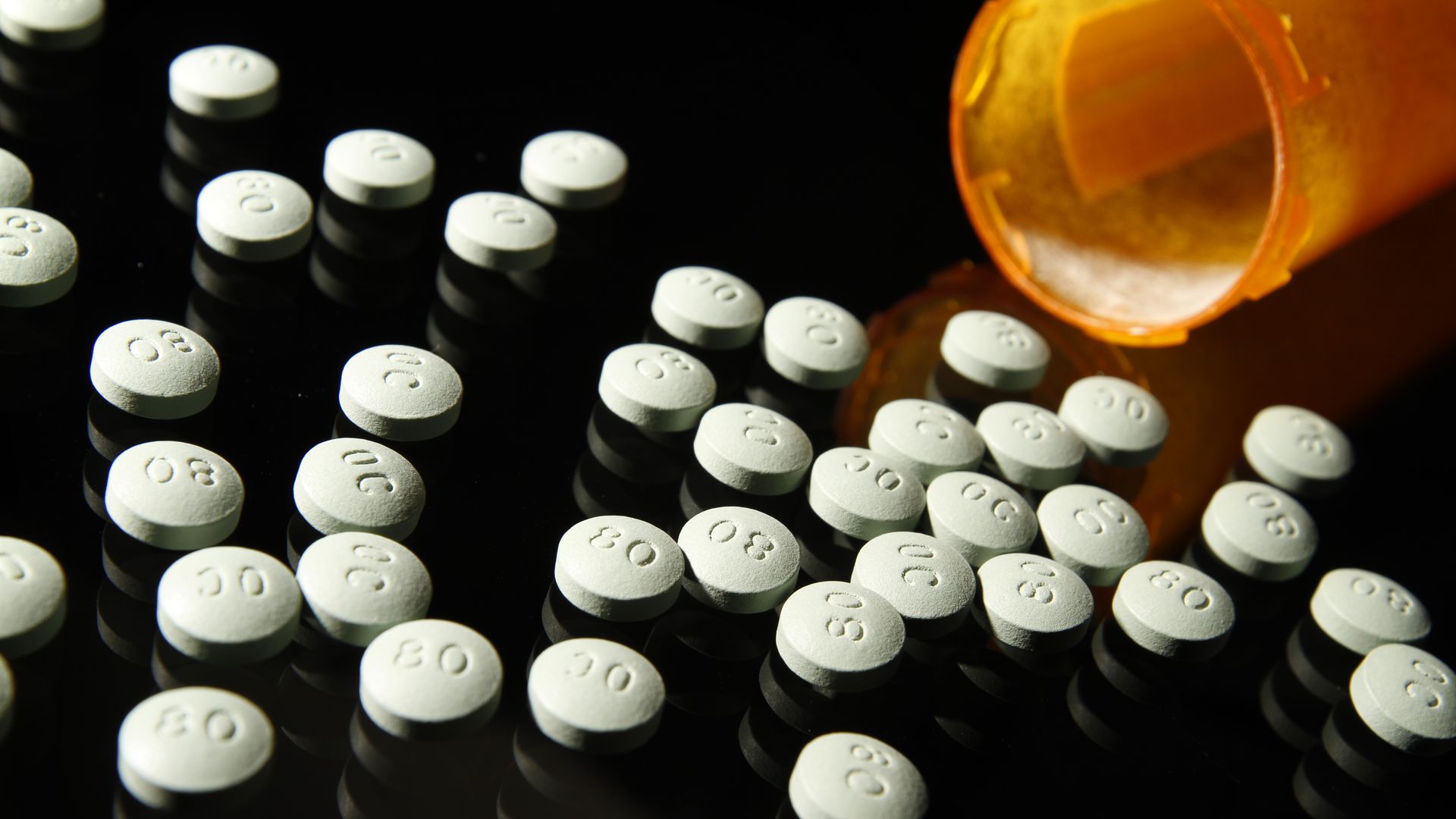OxyContin pills lay on a table with a bottle on its side.