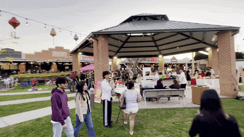 Image shows people walking in an open market area.