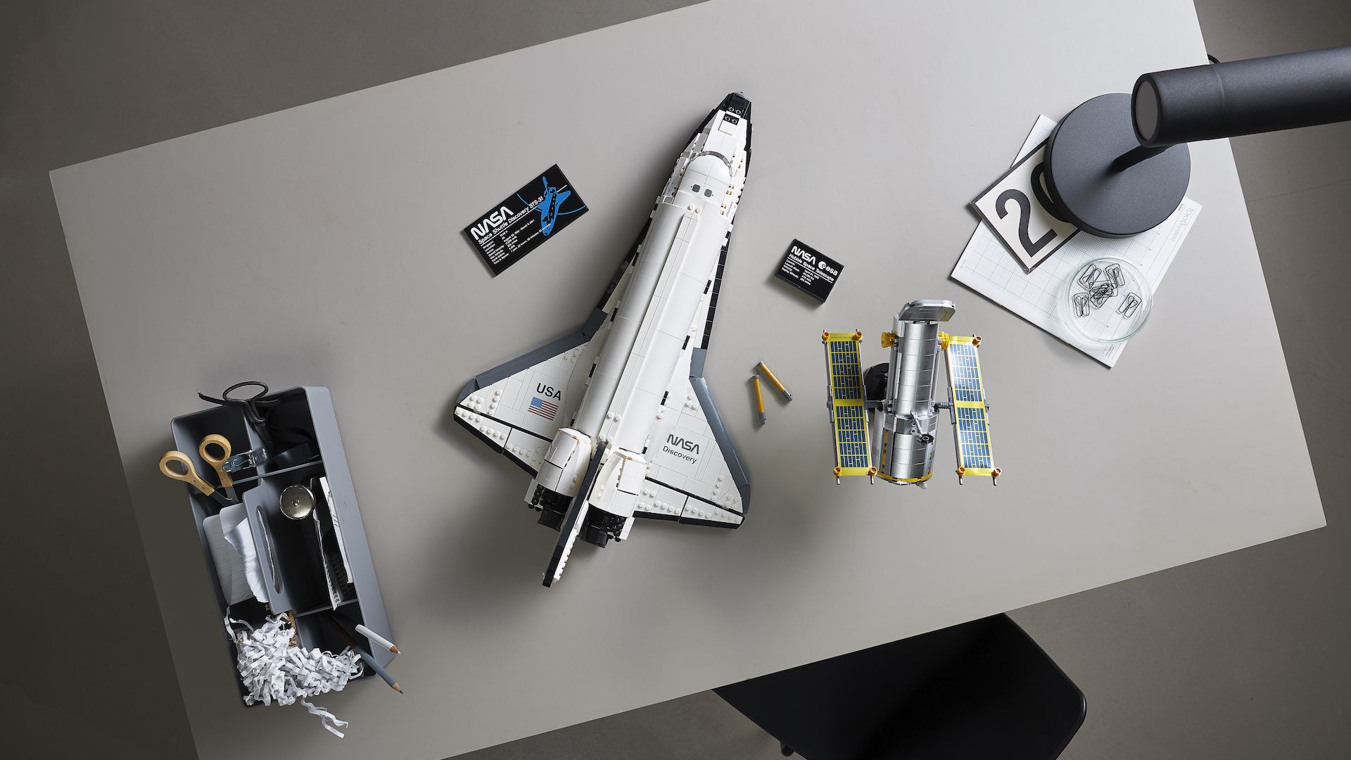 A Lego model of a space shuttle sitting on a table next to a model of the Hubble Space Telescope