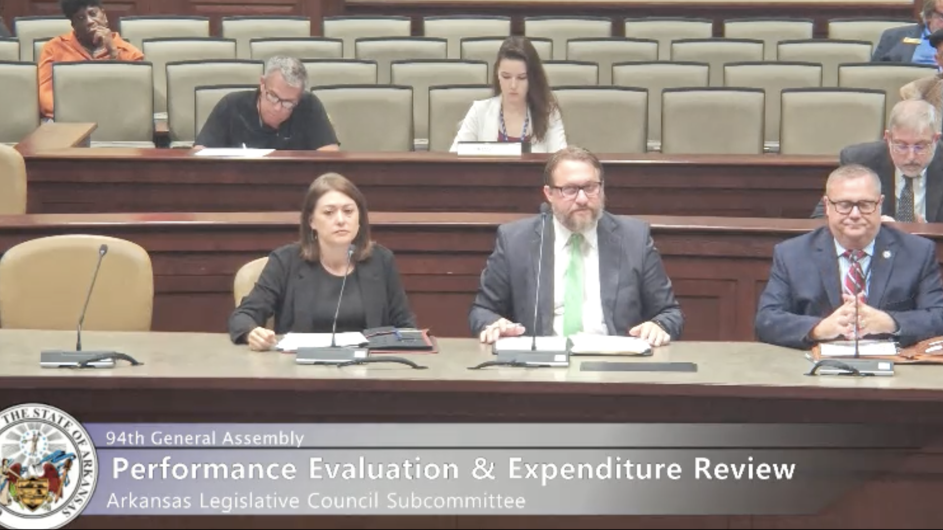 Three people sit in a legislative review committee.