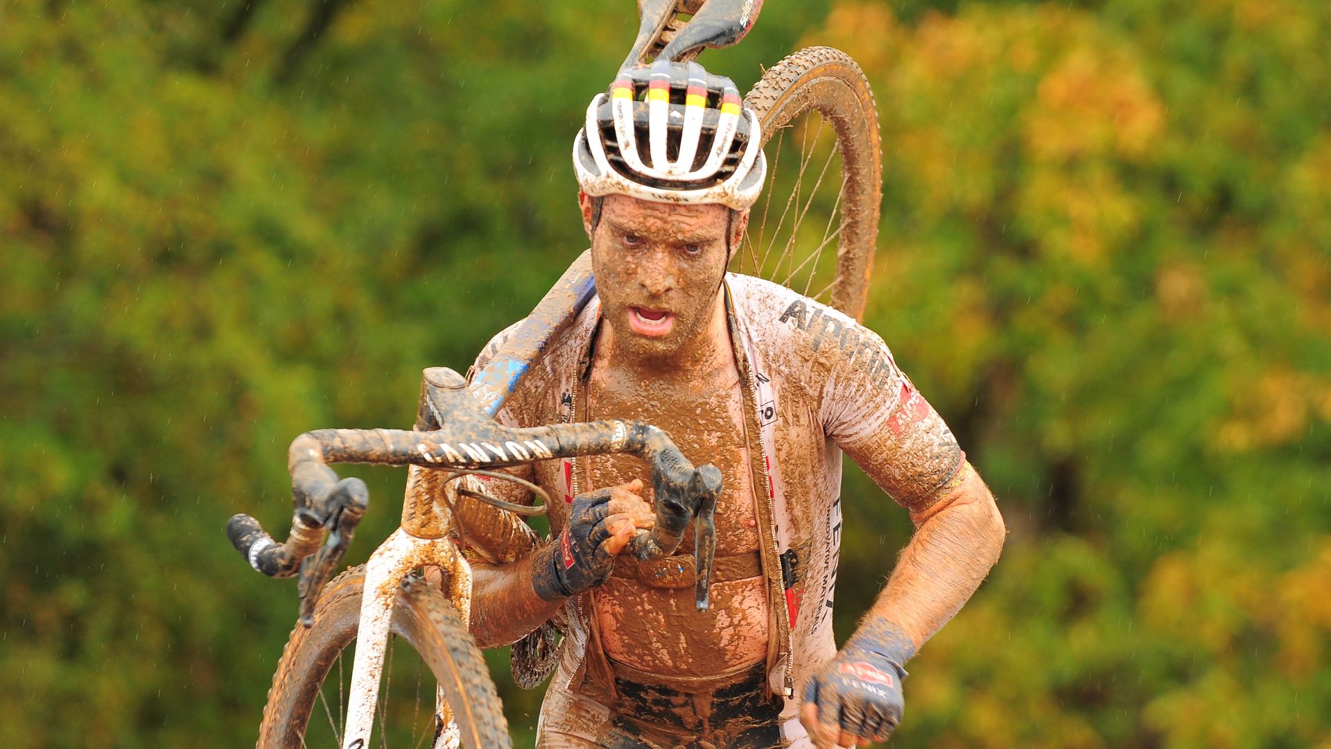 A muddy cyclist climbs stairs before riding down the other side.