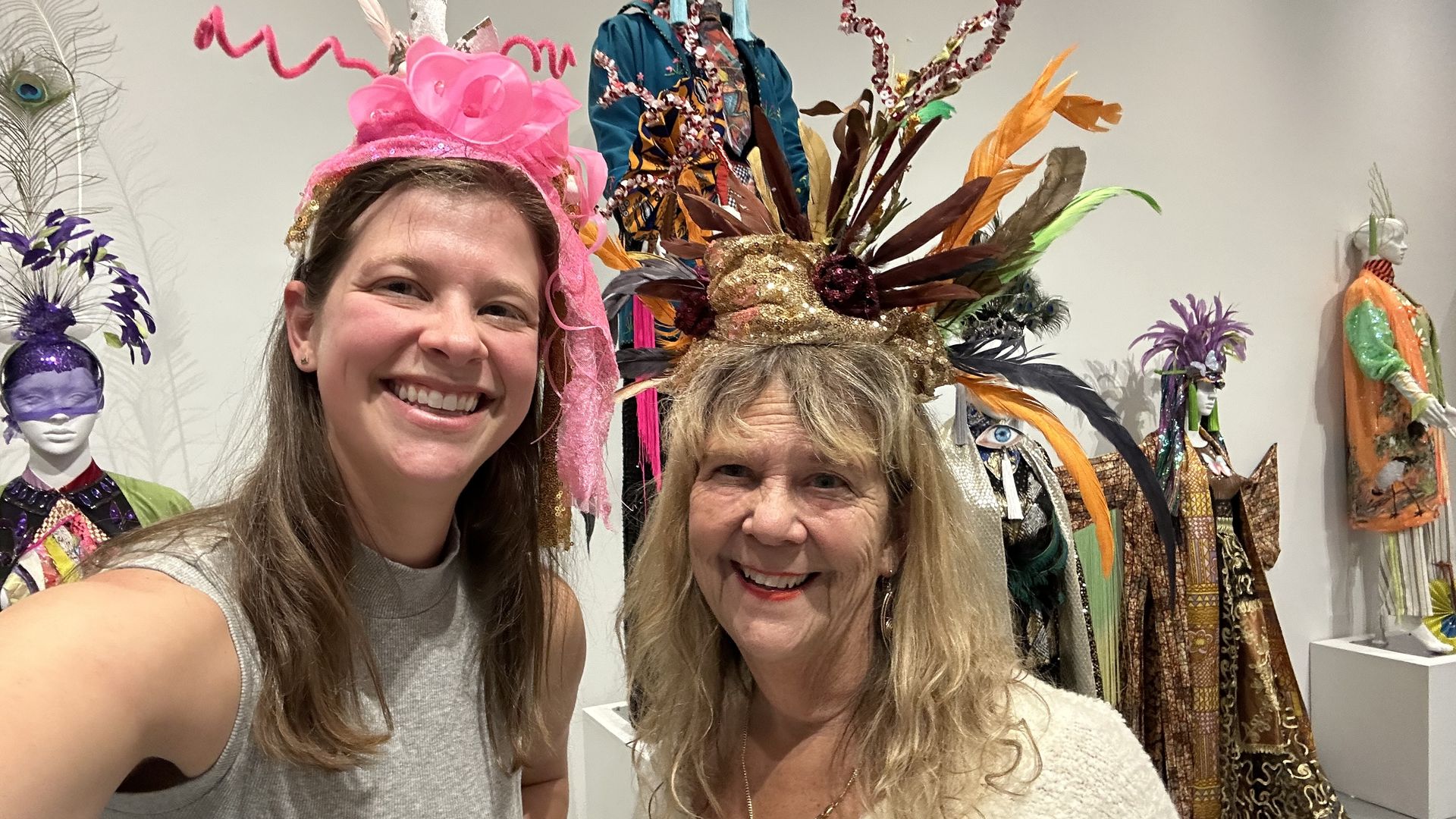 Two women, wearing multicolored headdresses, smile in a selfie.