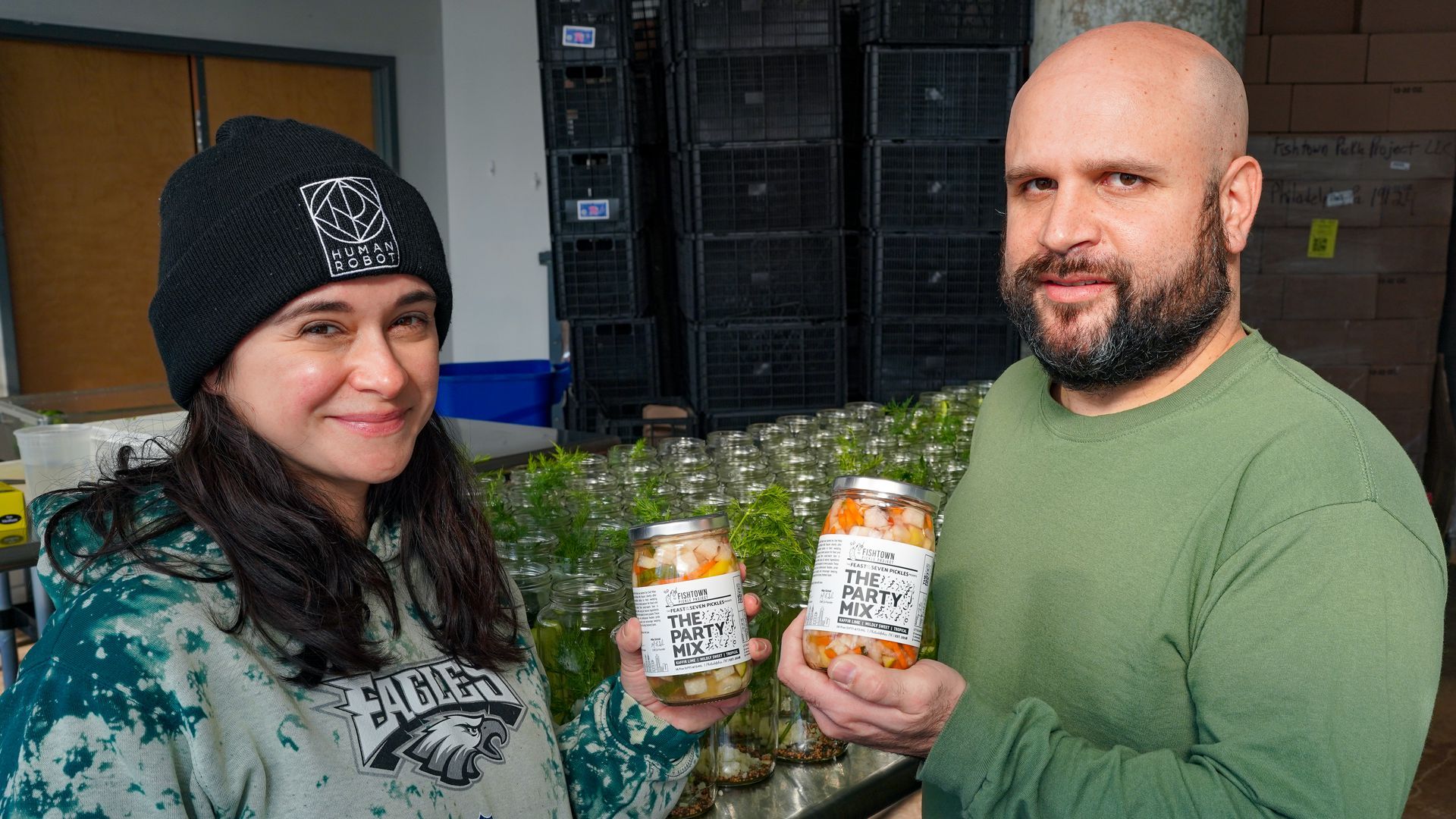 Niki Toscani and Mike Sicinski holding two jars of Fishtown Pickle Project Party Mix.