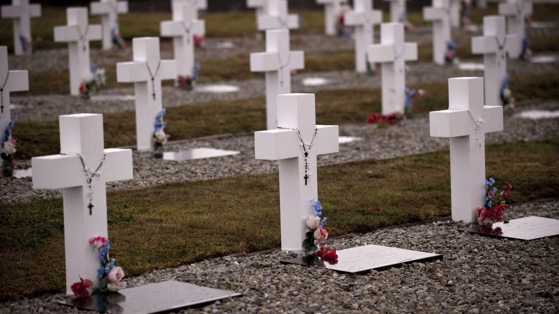 Plain white crosses, some with rosaries hanging, in a cemetery on the Malvinas Islands. 