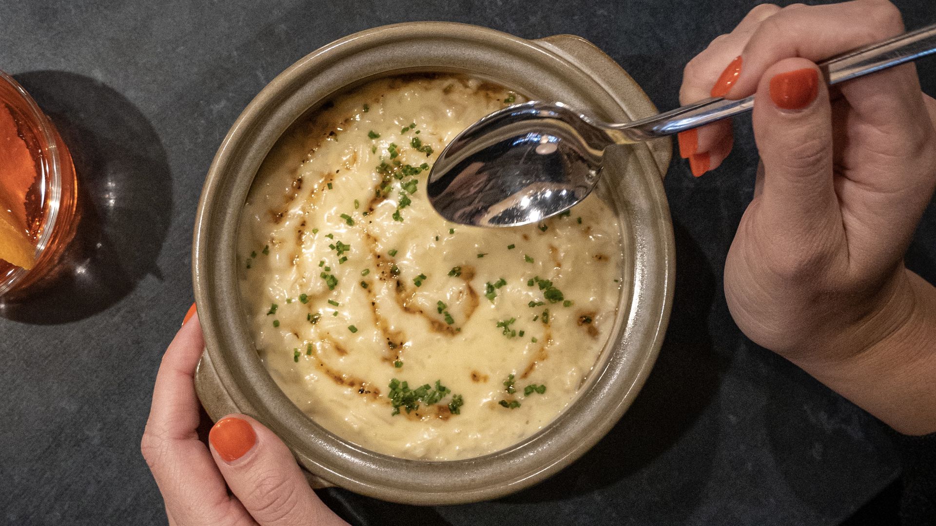 A person holding a bowl with one hand and a spoon in the other. The bowl is filled with creamy Koji Risotto.
