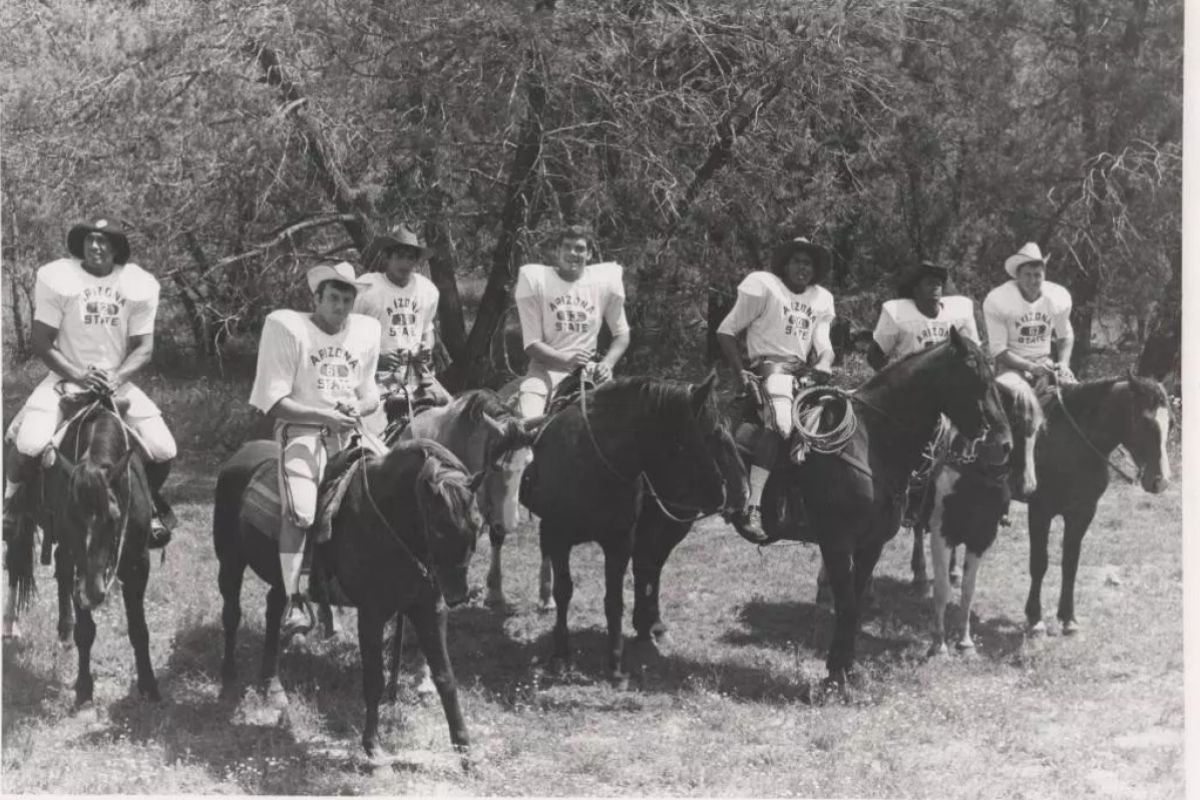 A black-and-white photo of football players on horses.