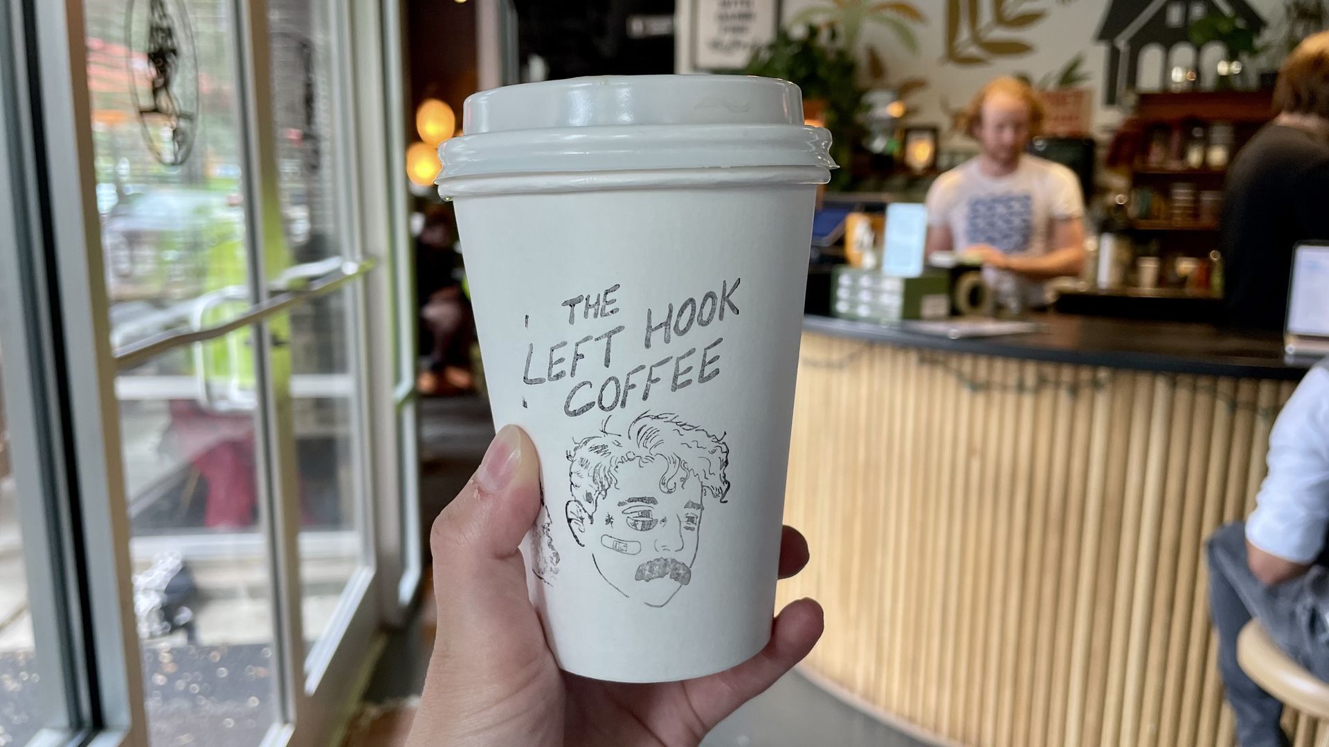 A coffee cup with the logo that says "The Left Hook Coffee"