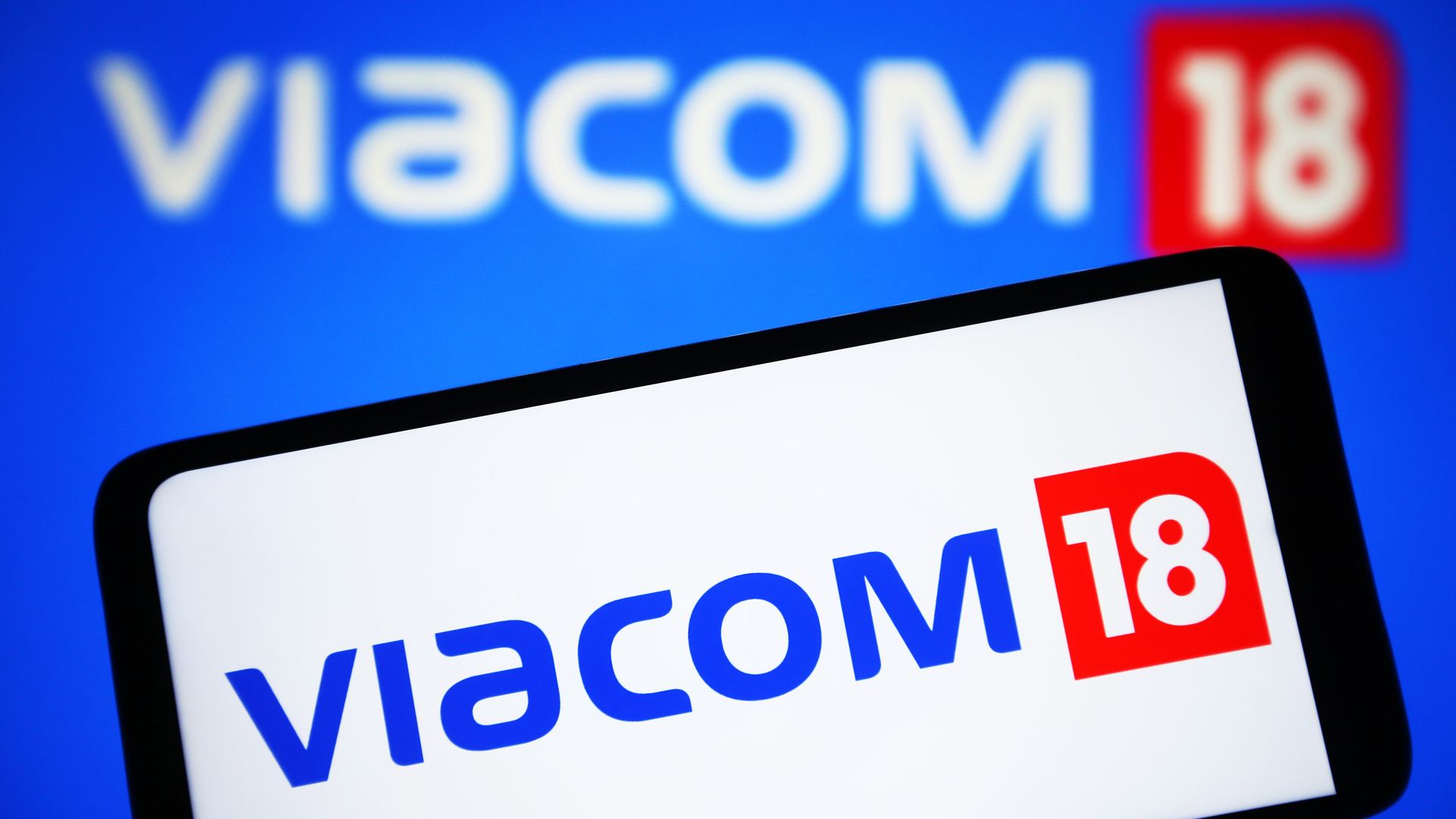 : In this photo illustration, Viacom18 Media Private Limited logo is seen on a smartphone and on a pc screen. 