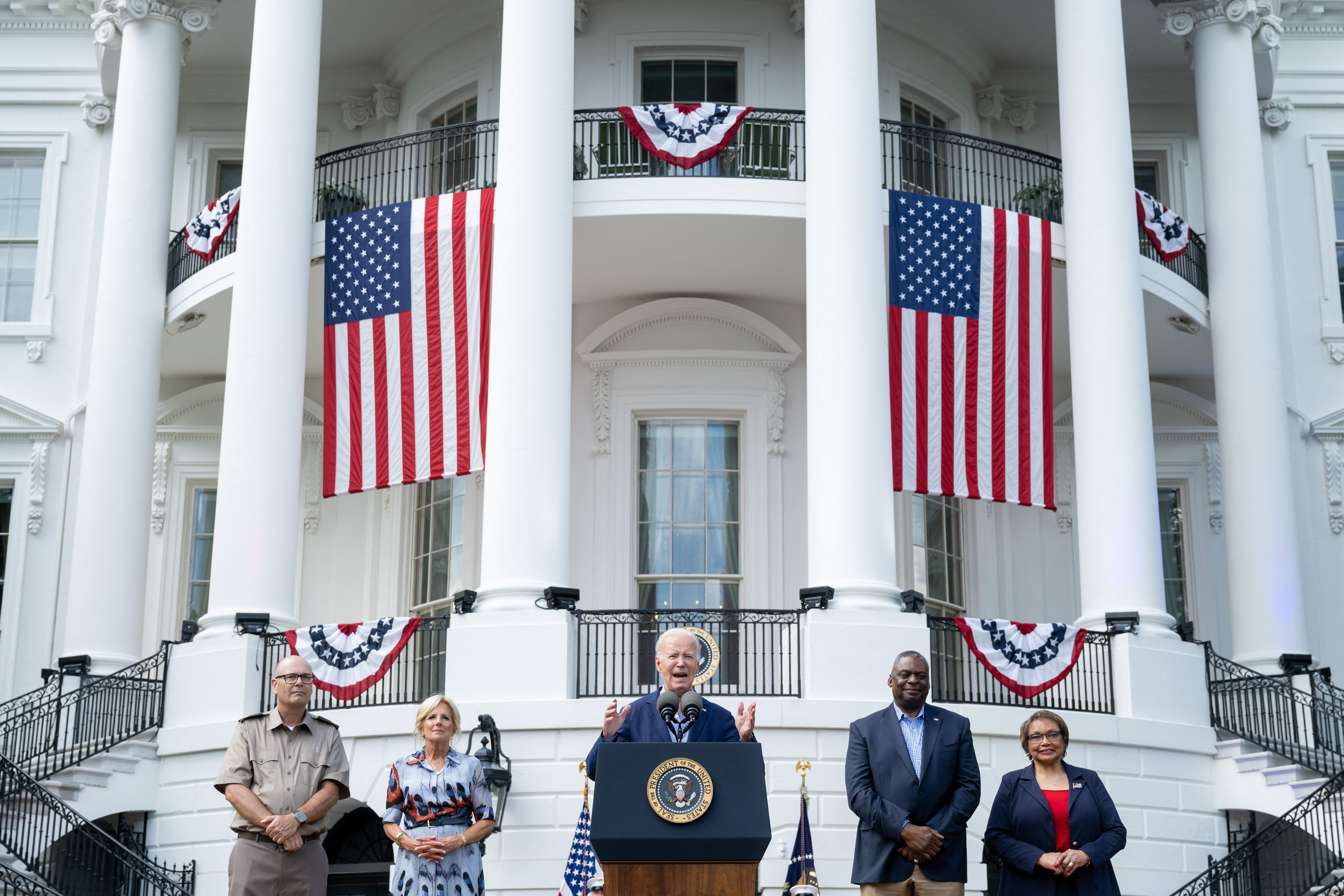 President Joe Biden speaks alongside First Lady Jill Biden (L) and Secretary of Defense Lloyd Austin (R) during a barbeque for active-duty military families in honor of the Fourth of July on the South Lawn of the White House in Washington, DC, July 4, 2023.