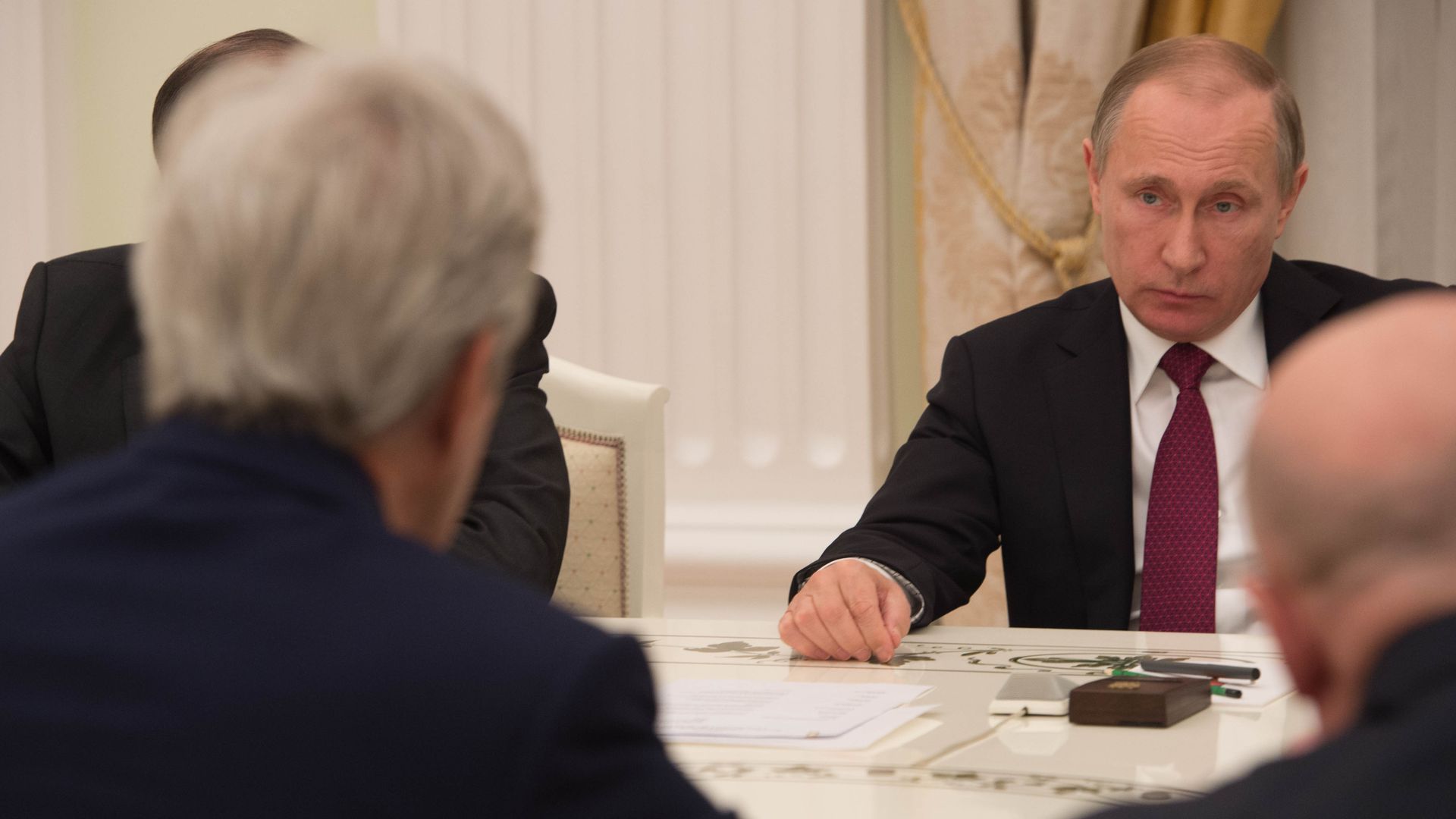 Russian President Vladimir Putin is seen listening to former Secretary of State John Kerry.