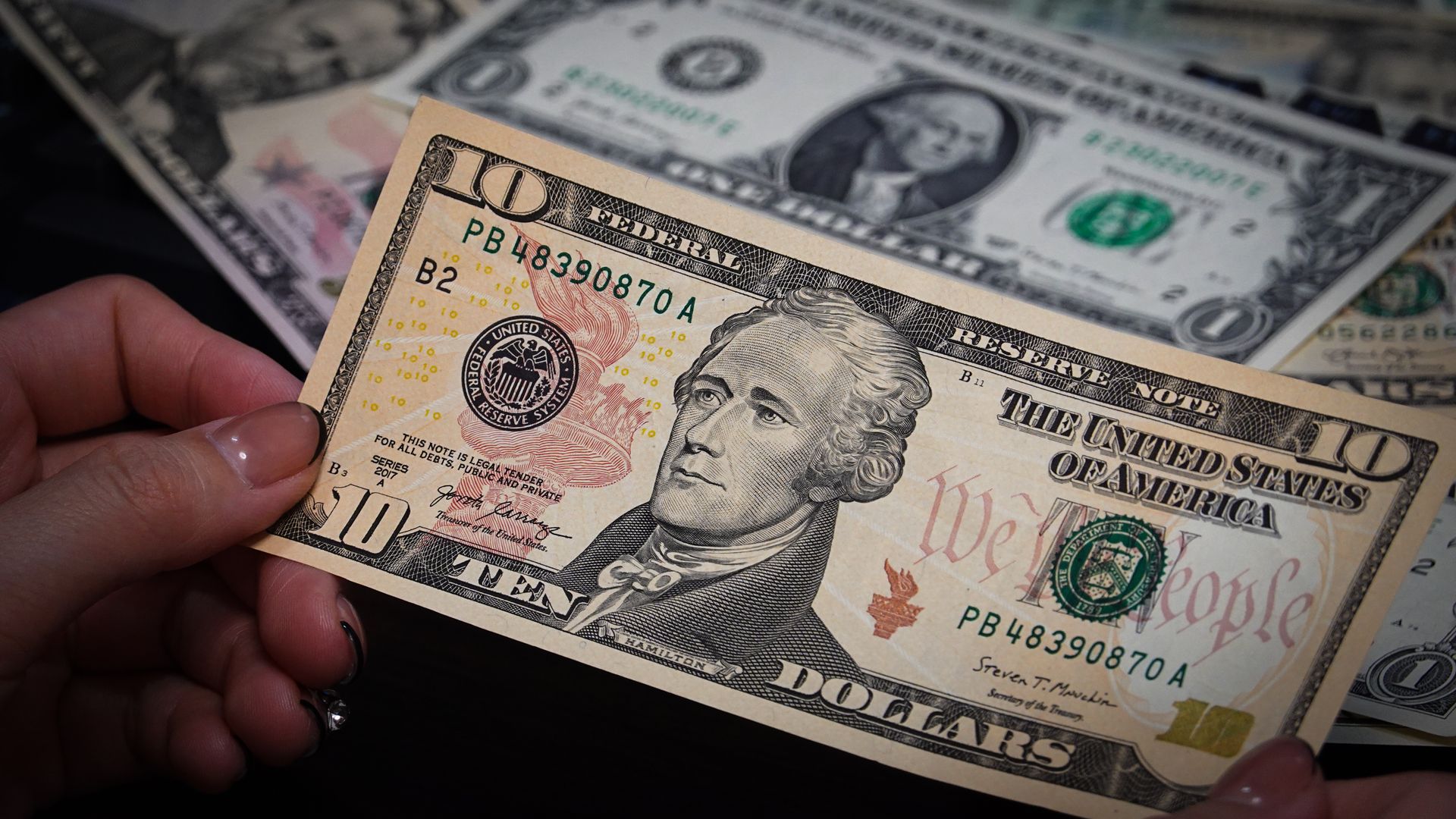 An illustration of a person is holding some US dollar cash bills in his hands