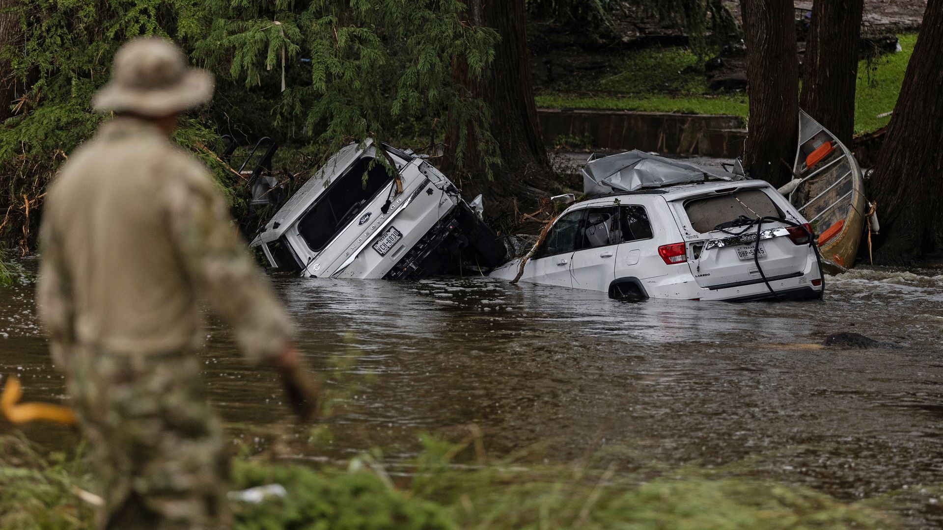 Vehicles sit submerged as a search and rescue worker looks through debris for any survivors or remains of people swept up in the flash flooding on July 6, 2025 in Hunt, Texas. Heavy rainfall caused flooding along the Guadalupe River in central Texas with multiple fatalities reported.