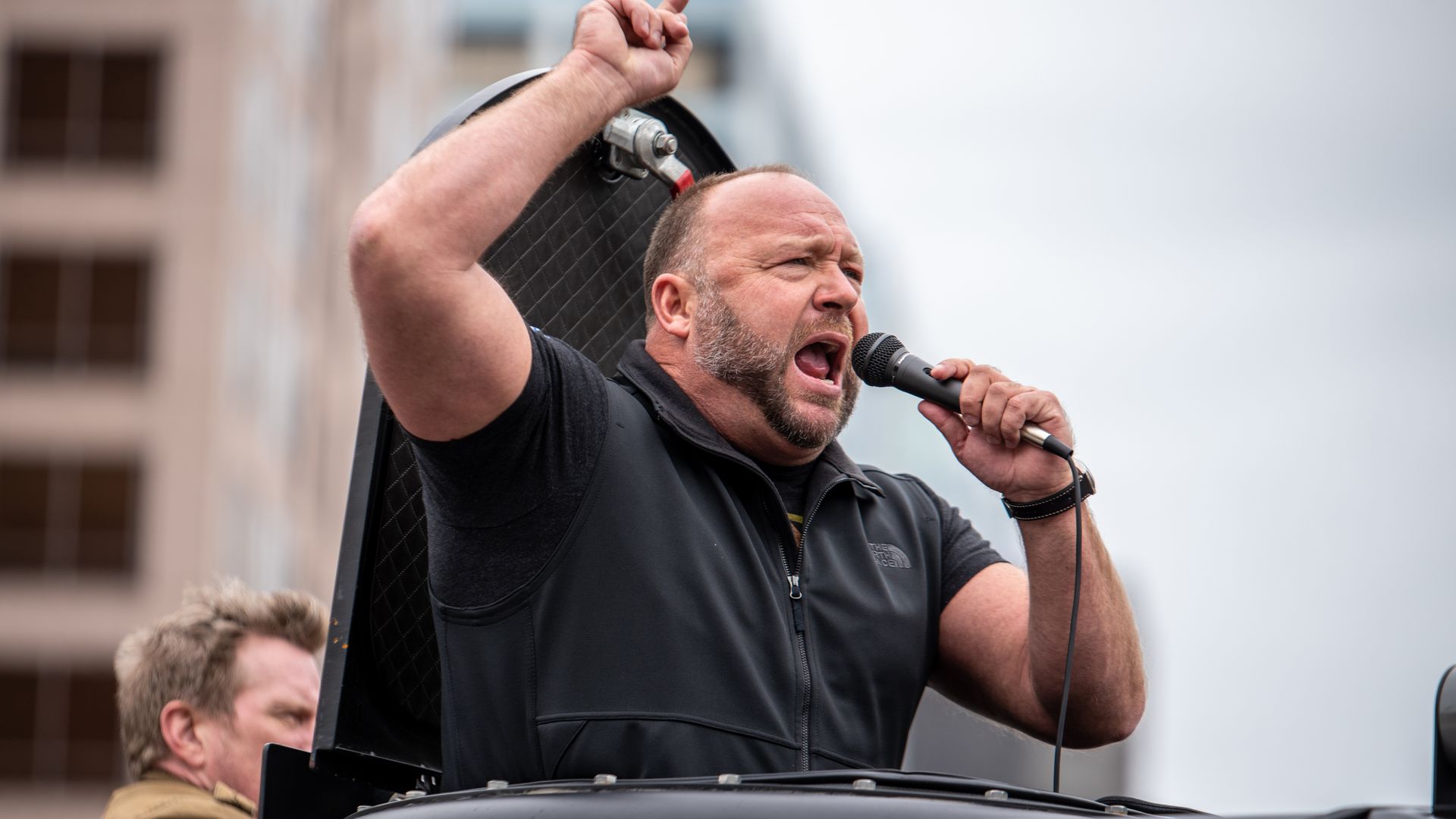 Picture of Alex Jones standing in a car yelling into a microphone